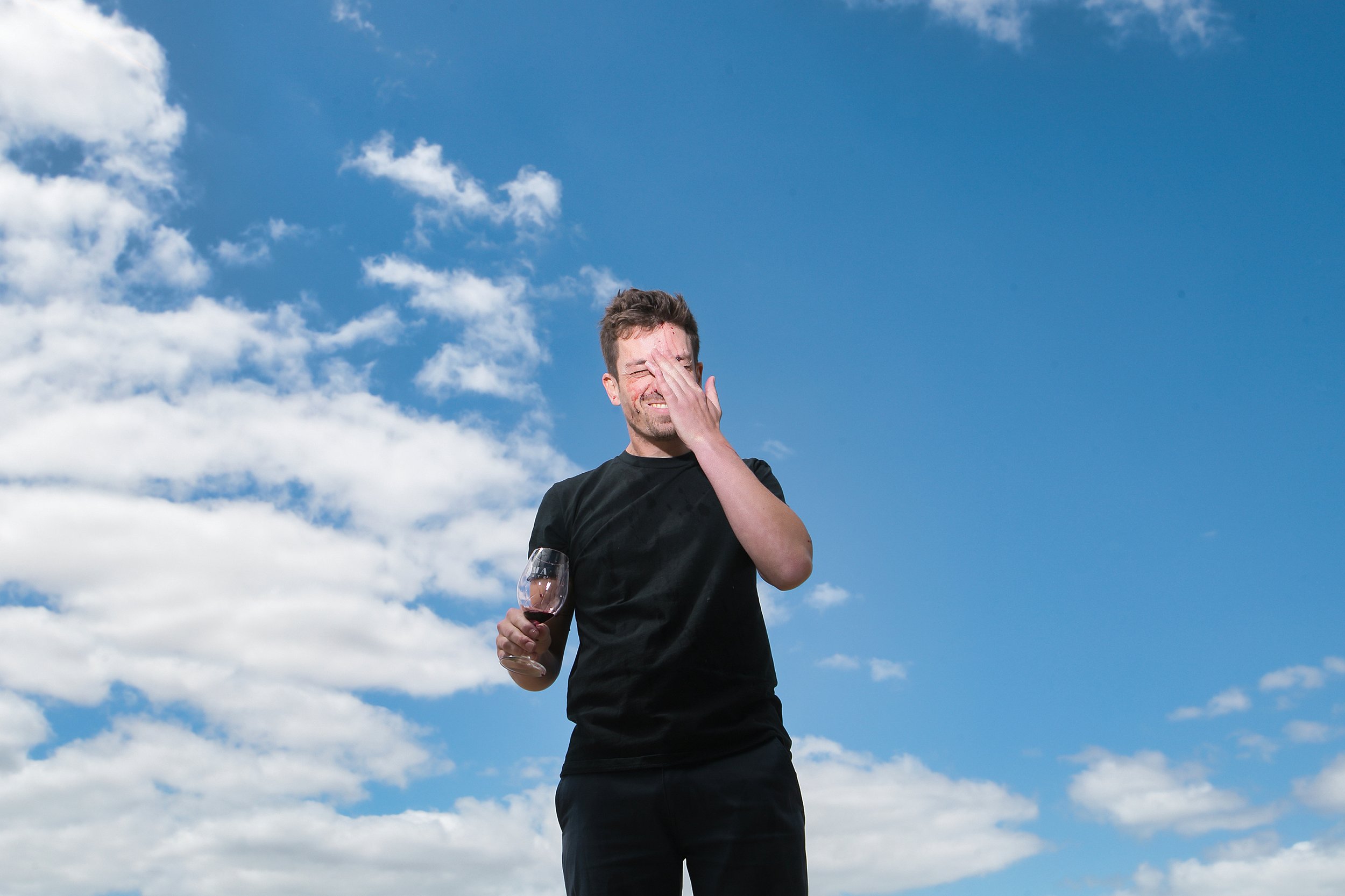 Picture of winemaker Lewis White with a wine glass in his hand, blue sky behind him.