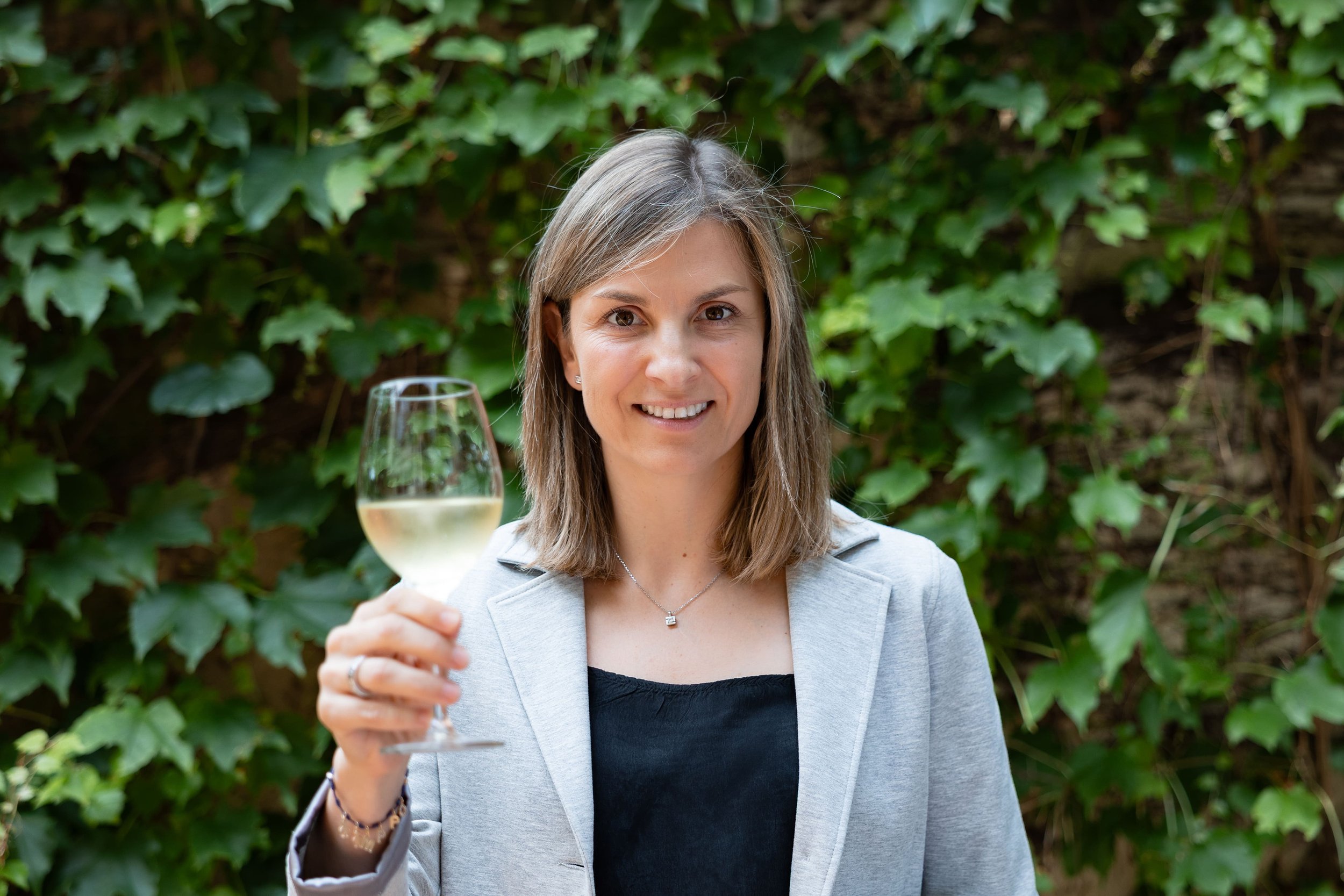 Marta Vidal, new president DO Cava, holds a glass of CAVA sparkling wine in celebration.