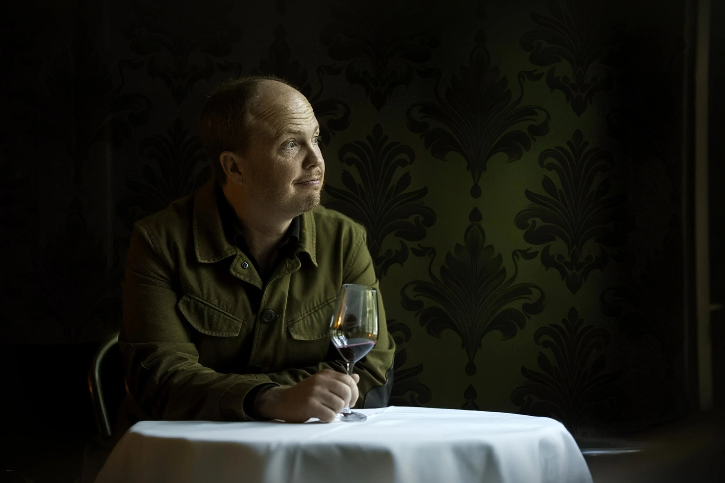 Voyager Estate winemaker Tim Shand sits at a dining table with a glass of wine in his hand.