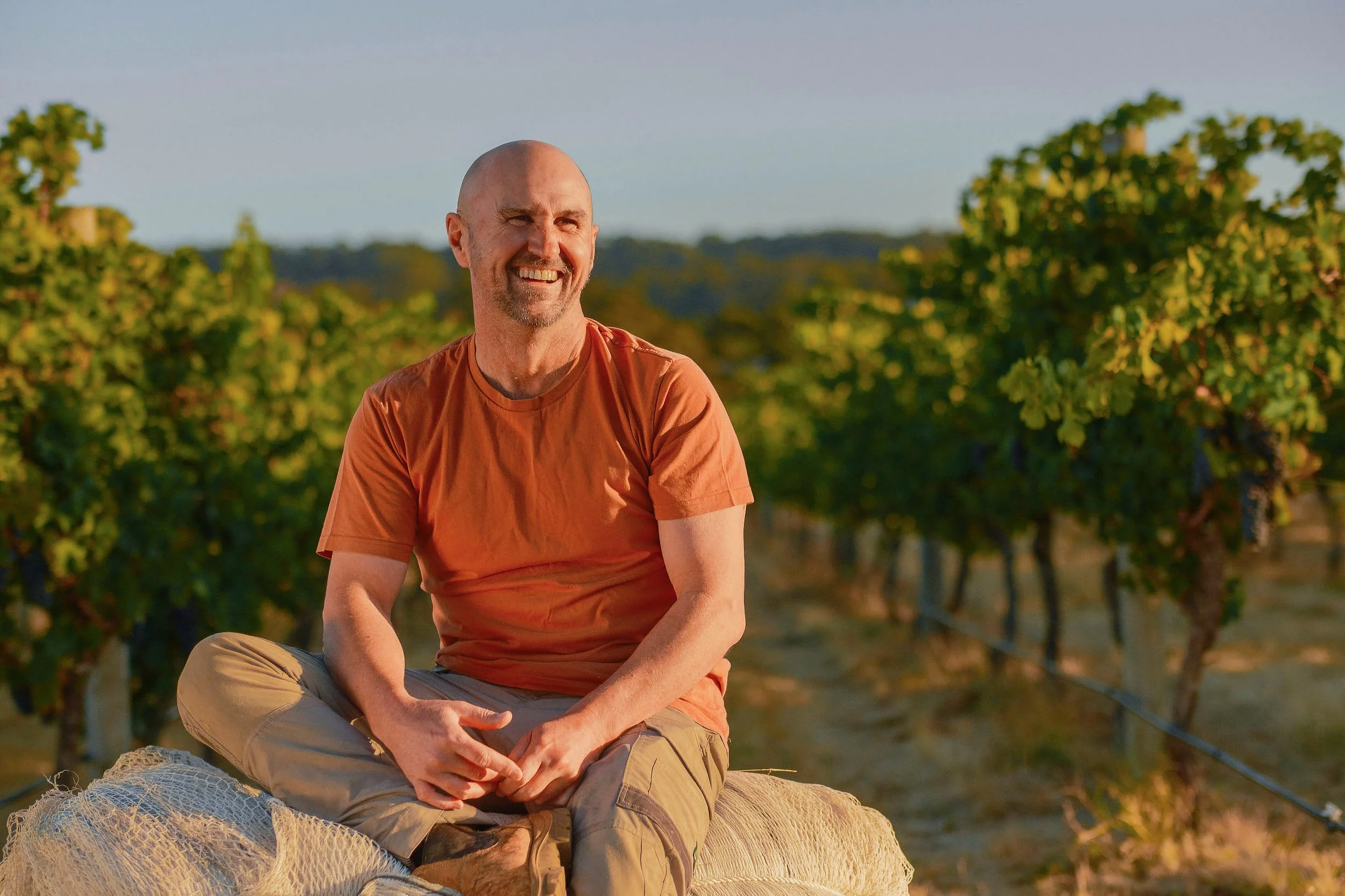 Xanadu Winemaker Glenn Goodall in a vineyard in Margaret River, in golden hour sunshine.