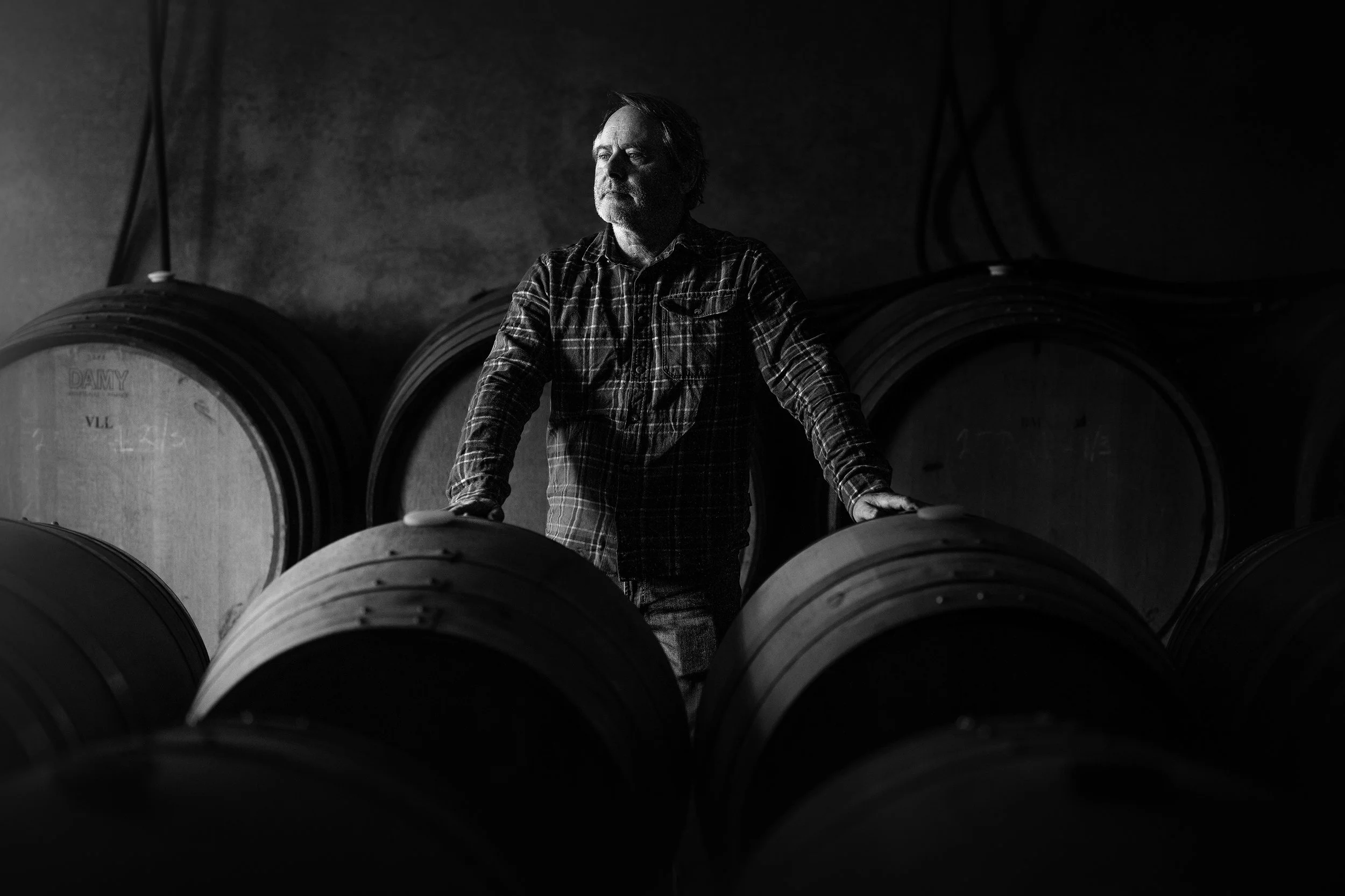 Winemaker Steve Lubiana, of Stefano Lubiana Wines, in the barrel room at the winery. staring towards the light, in black and white.