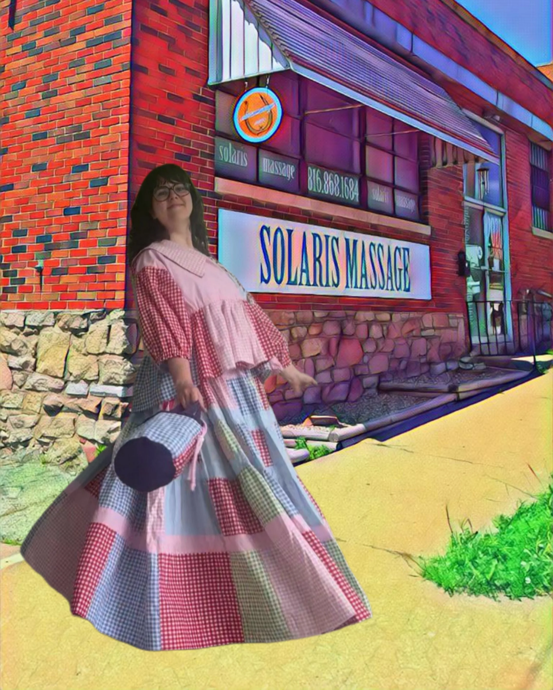 Judith smiling outside Solaris Massage, wearing a colorful patchwork dress in front of the brick storefront and Solaris Massage sign.