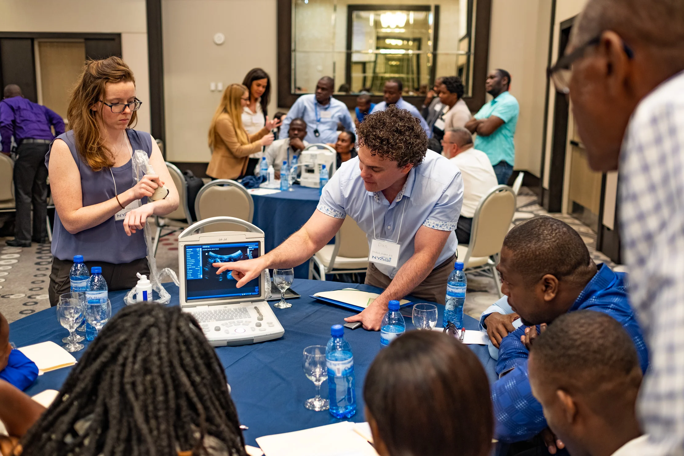 NYAGI volunteers, Codee Champney (left) and Dan Coates (center), introduce a group of Haitian doctors to the new ultrasound machines as part of the first day’s technical orientation.