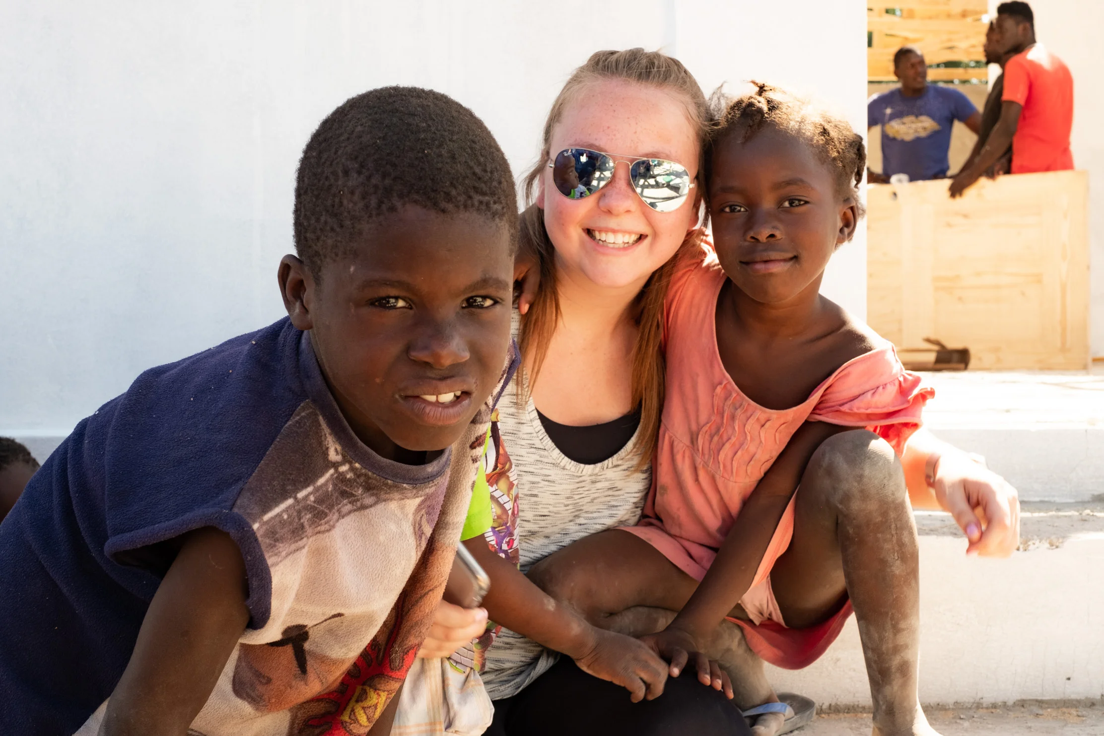 NYAGI volunteer, Becca Makens, with kids outside a new community center being built in Chambrun, just outside Port-au-Prince, Haiti.