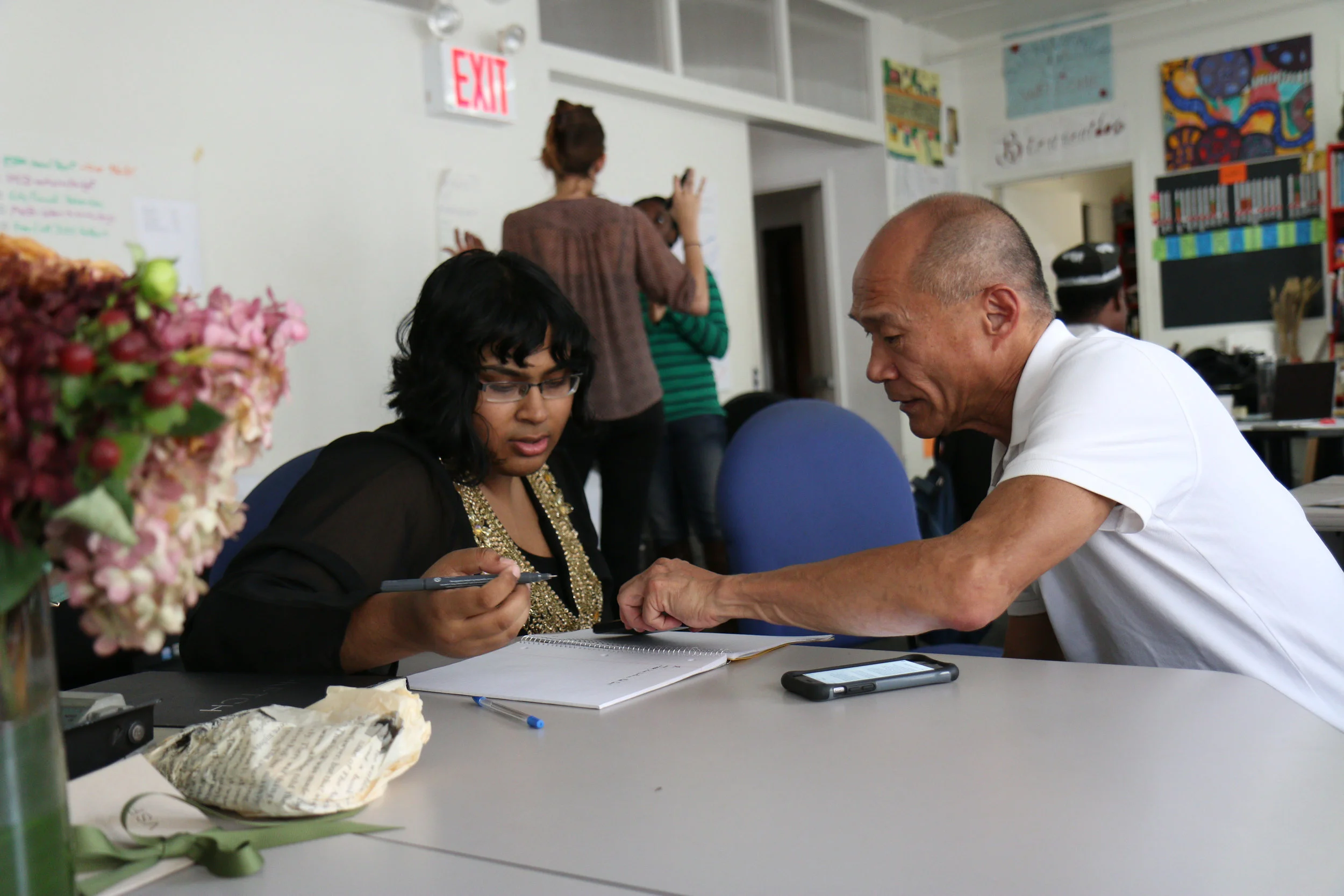 Man assisting woman to fill in a form whilst seated