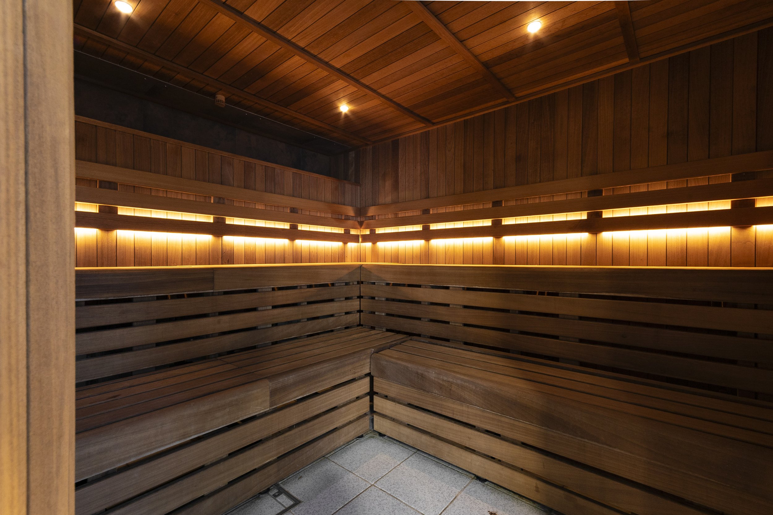 Wood-panelled sauna with warm strip lighting and tiered seating