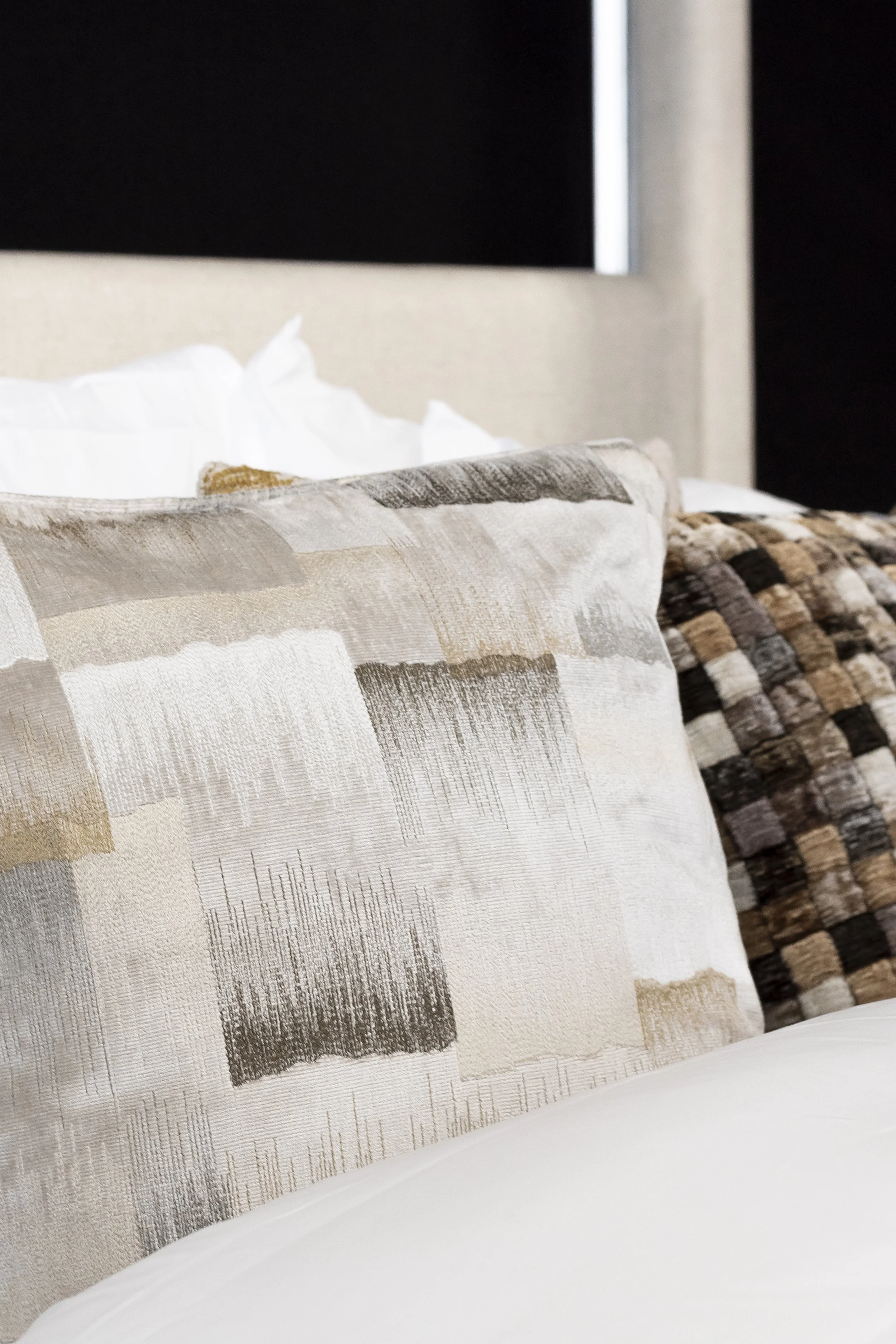 Bed with grey and cream textured cushions on white linen _Furnishing Futures