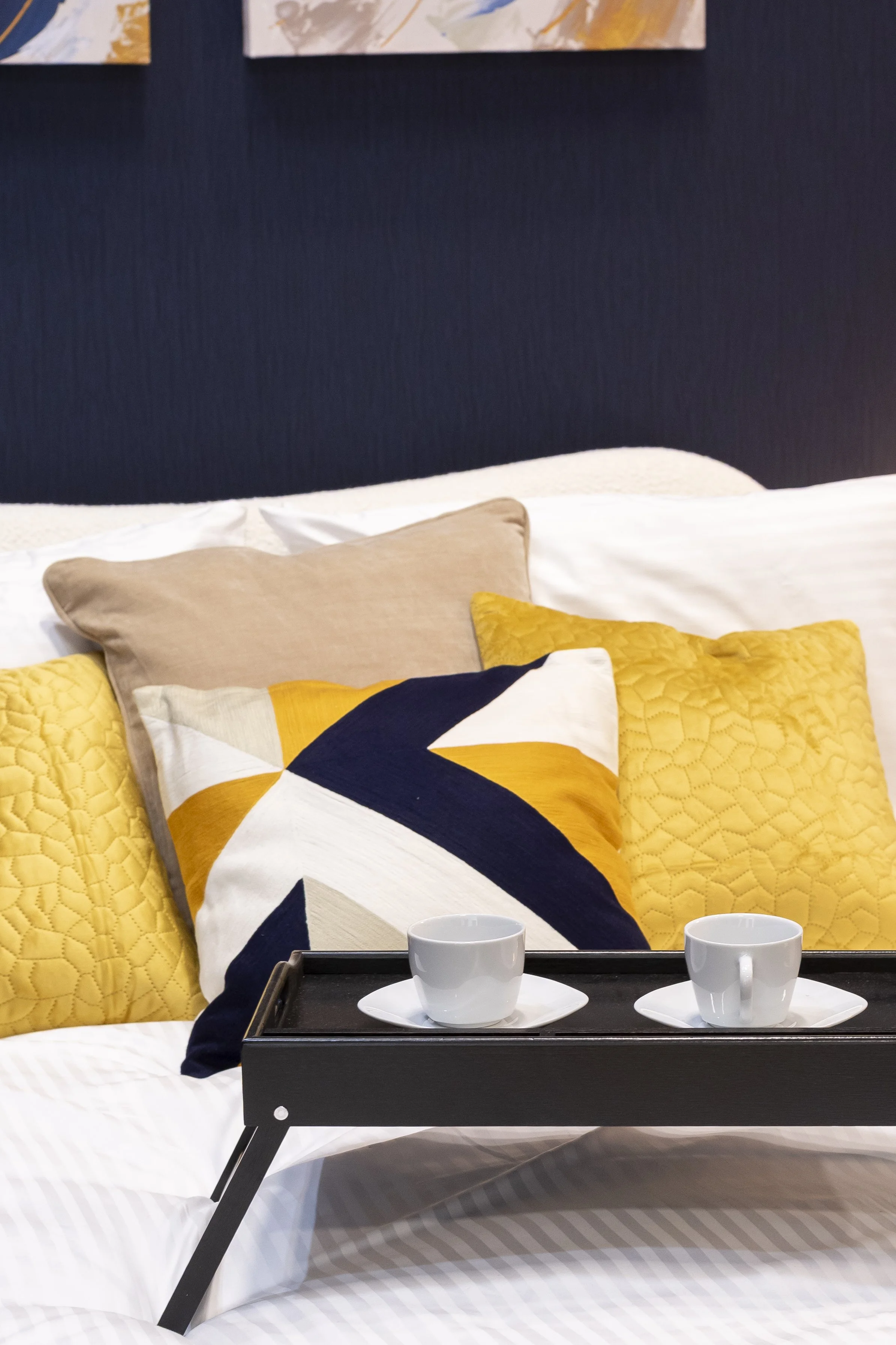 Bed tray with cups on navy and mustard cushions_Wayfair Professional