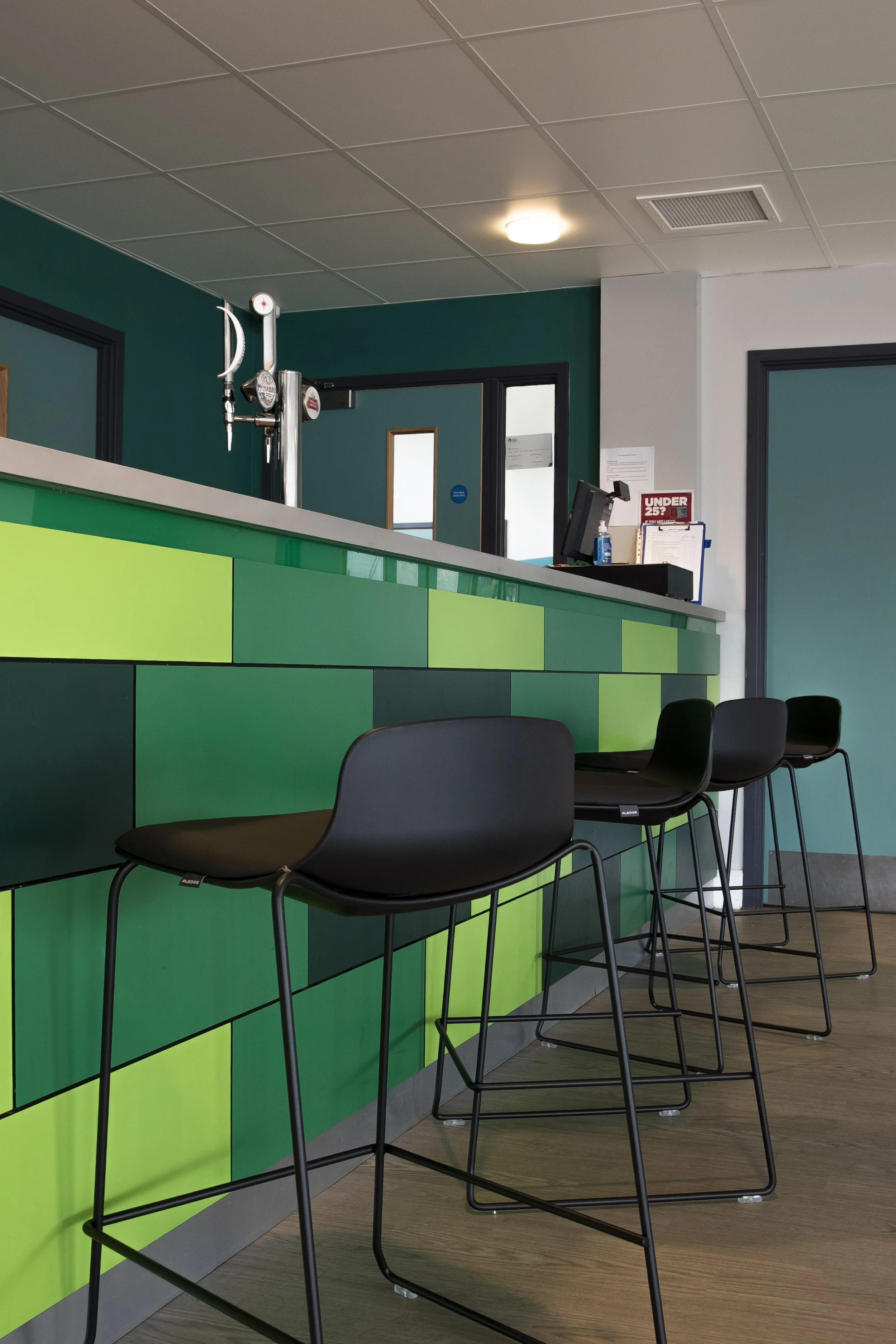Green block-tiled bar with black bar stools