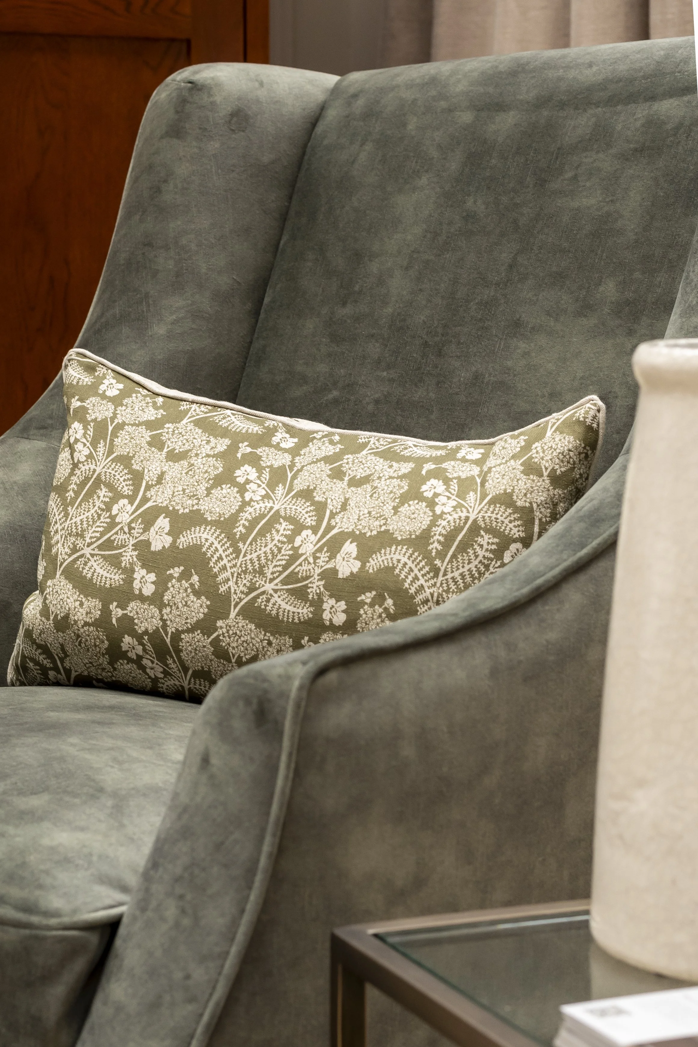 Green velvet armchair with a patterned cushion_The Cotswold Company | B Corp™