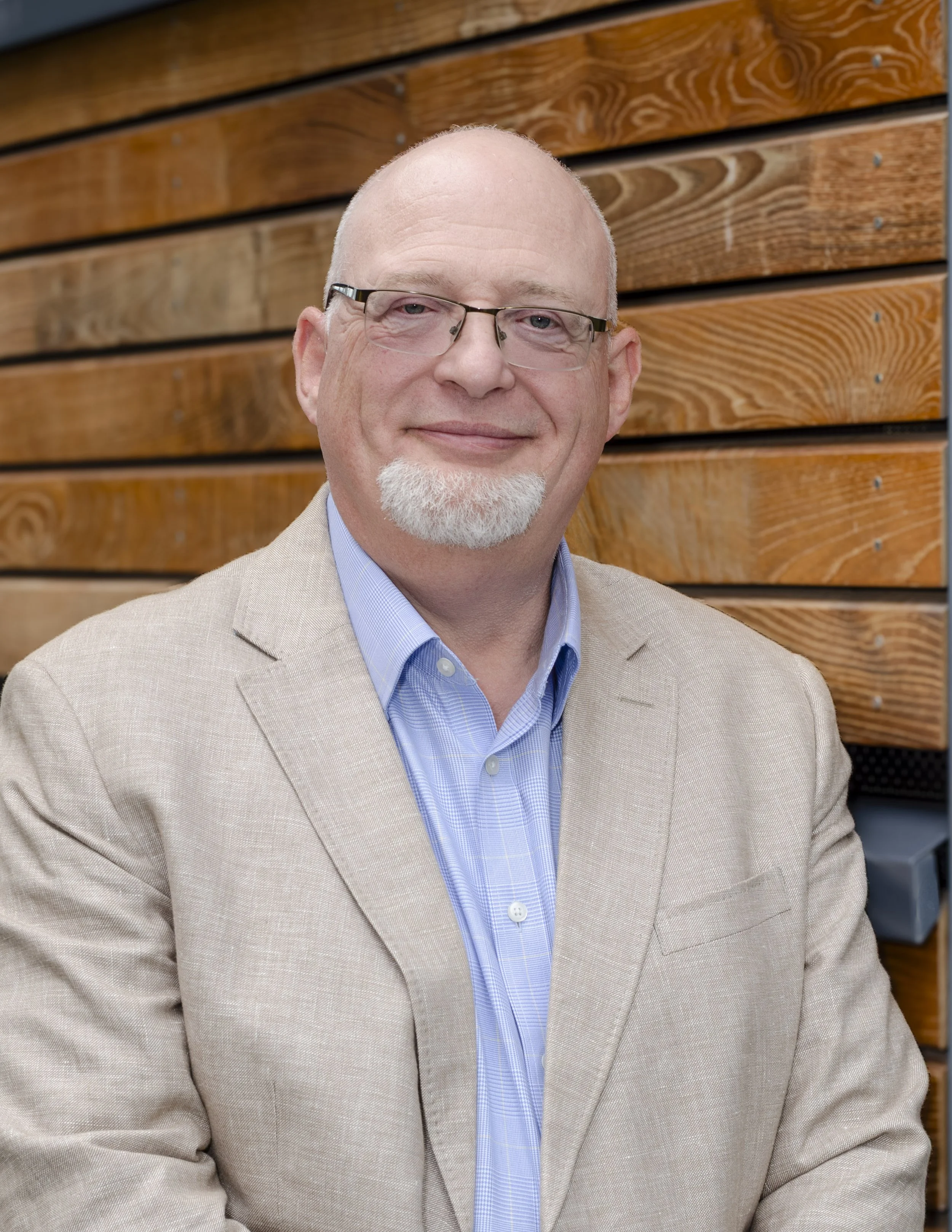 Mark Spence in a beige blazer and blue shirt in front of timber cladding
