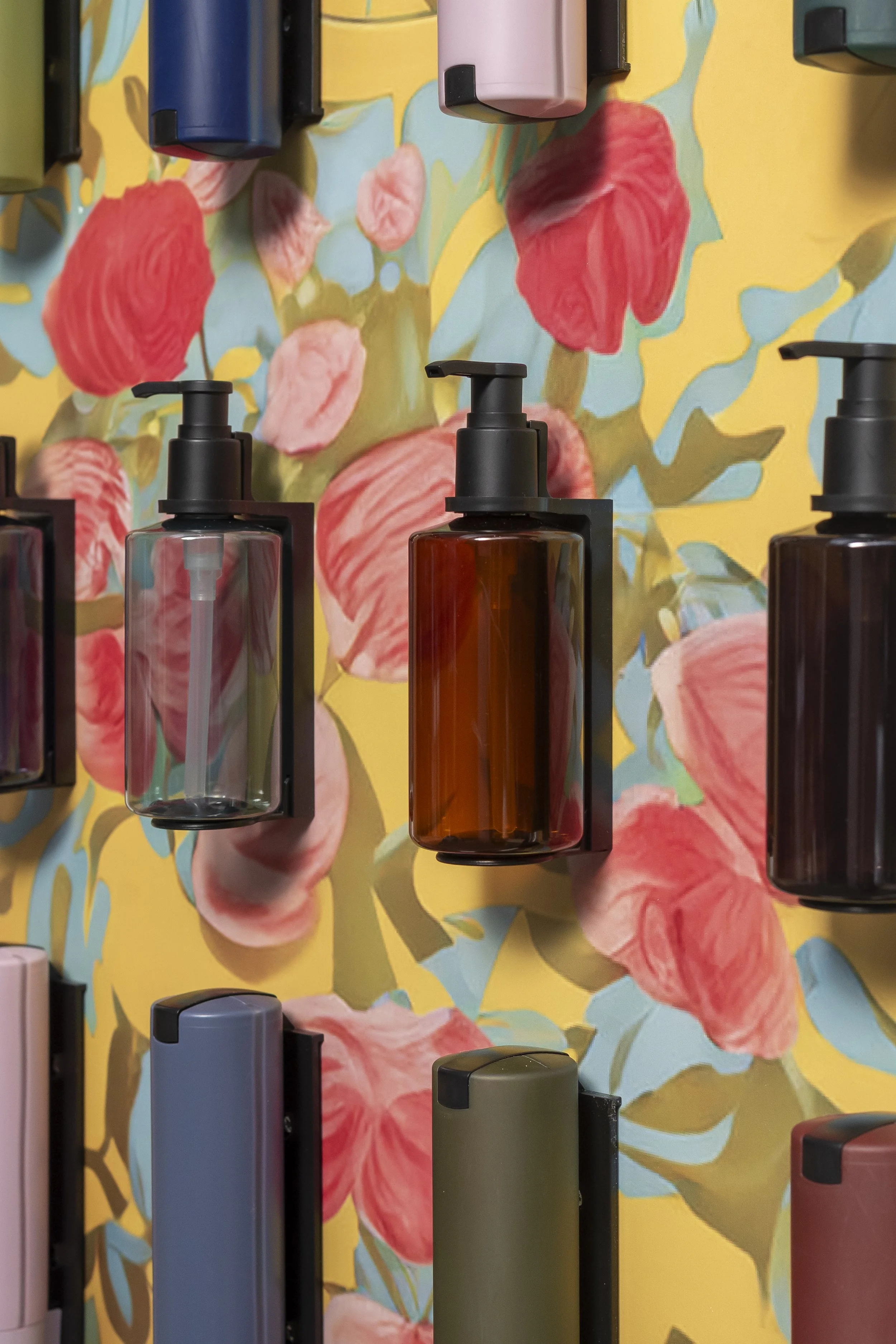 Colourful floral print panel with amber toiletry bottles_ADA Cosmetics