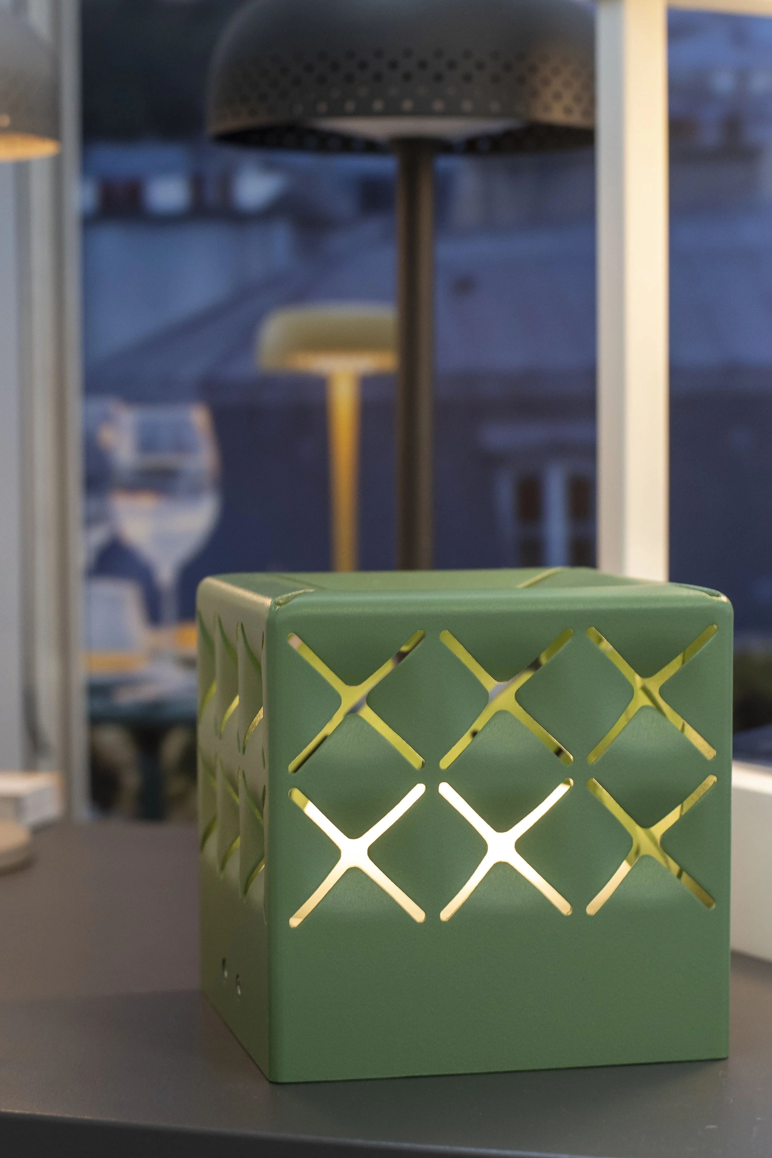 Green lantern with a cut-out pattern on a terrac_Lumenform