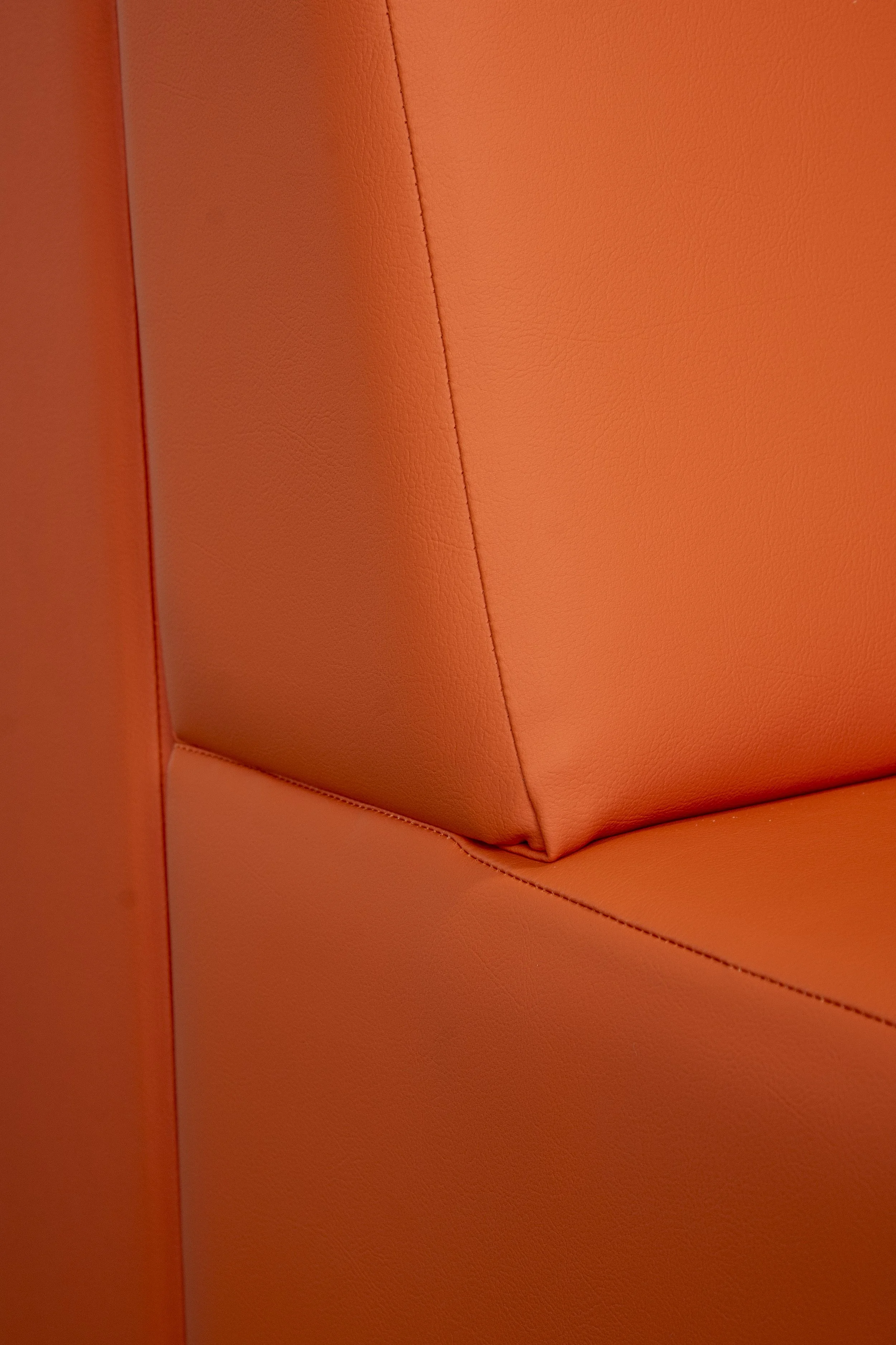 Close-up of orange upholstered seating with a piped seam
