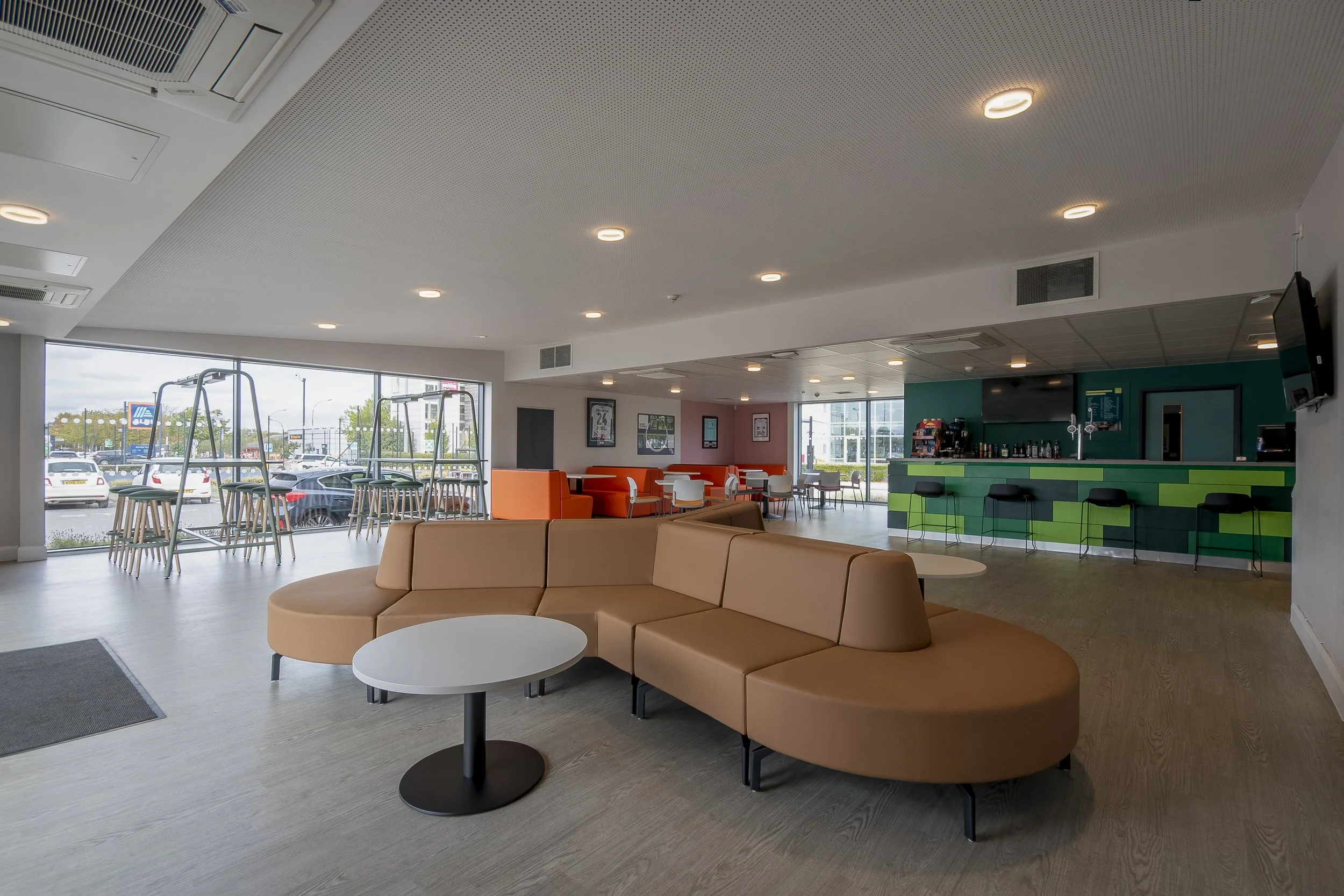 Café and lounge area with orange booths, white tables and grey chairs with coloured seats, photographed for interior photography