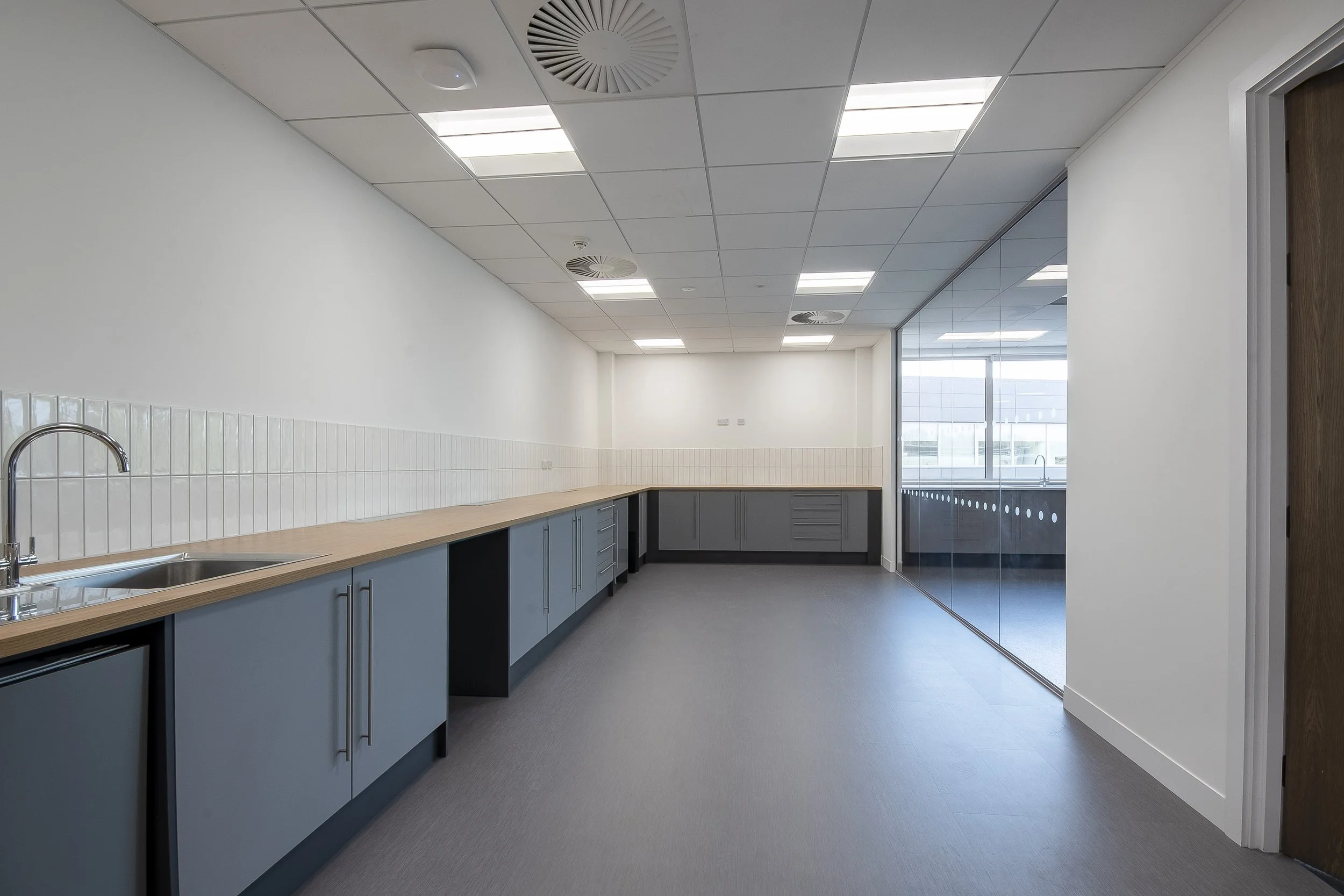 Long kitchenette with timber worktop, sink and blue-grey cabinets