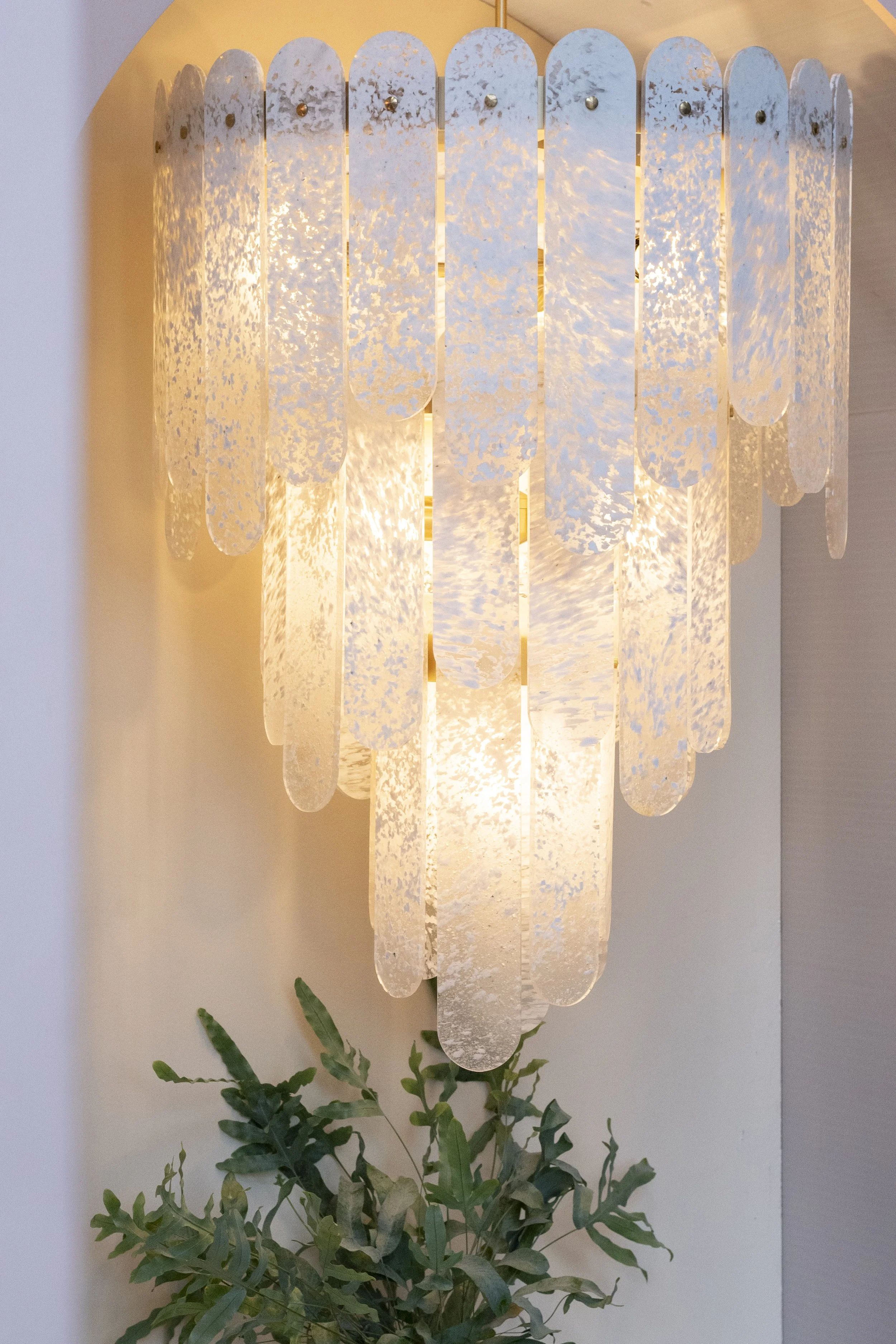 Layered glass chandelier beside a green plant_SPARK & BELL