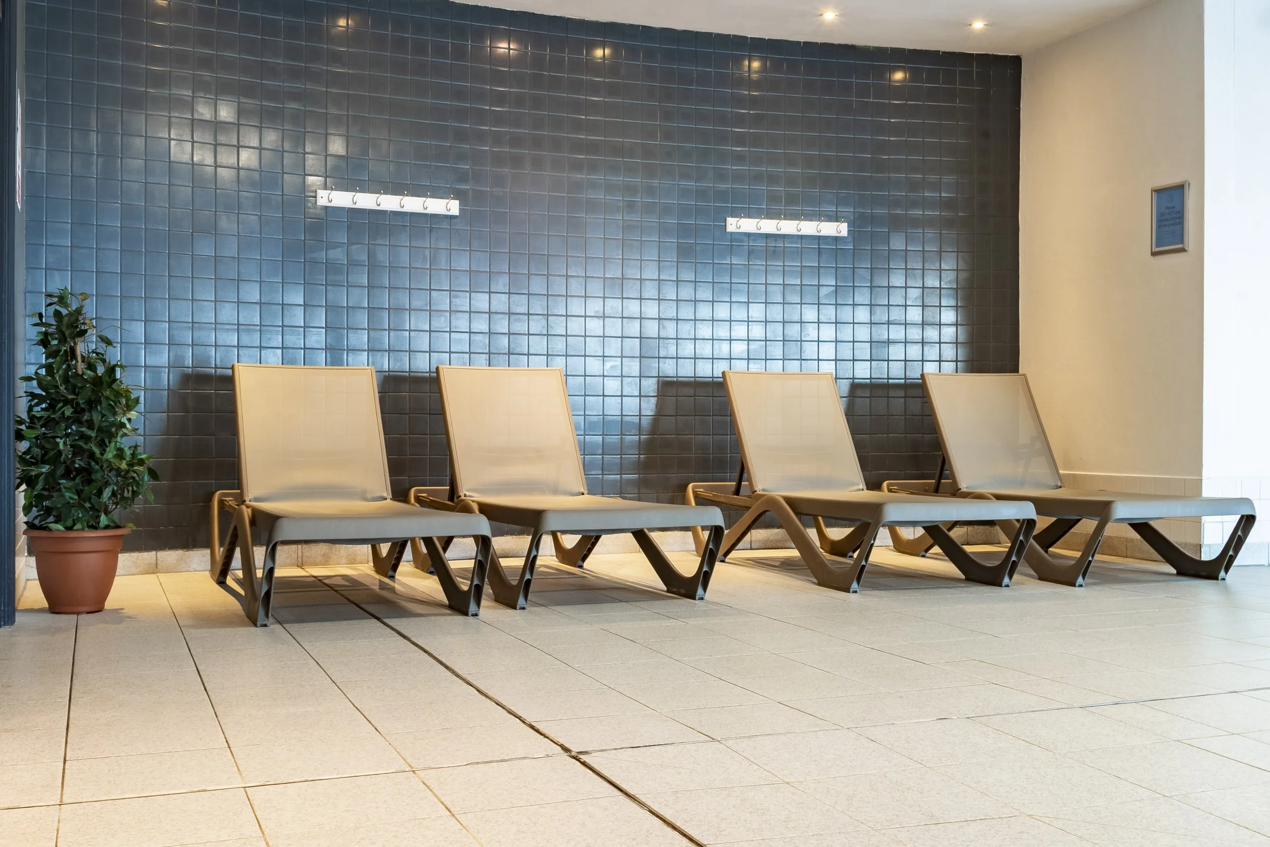 Relaxation area with sun loungers in front of a blue tiled wall