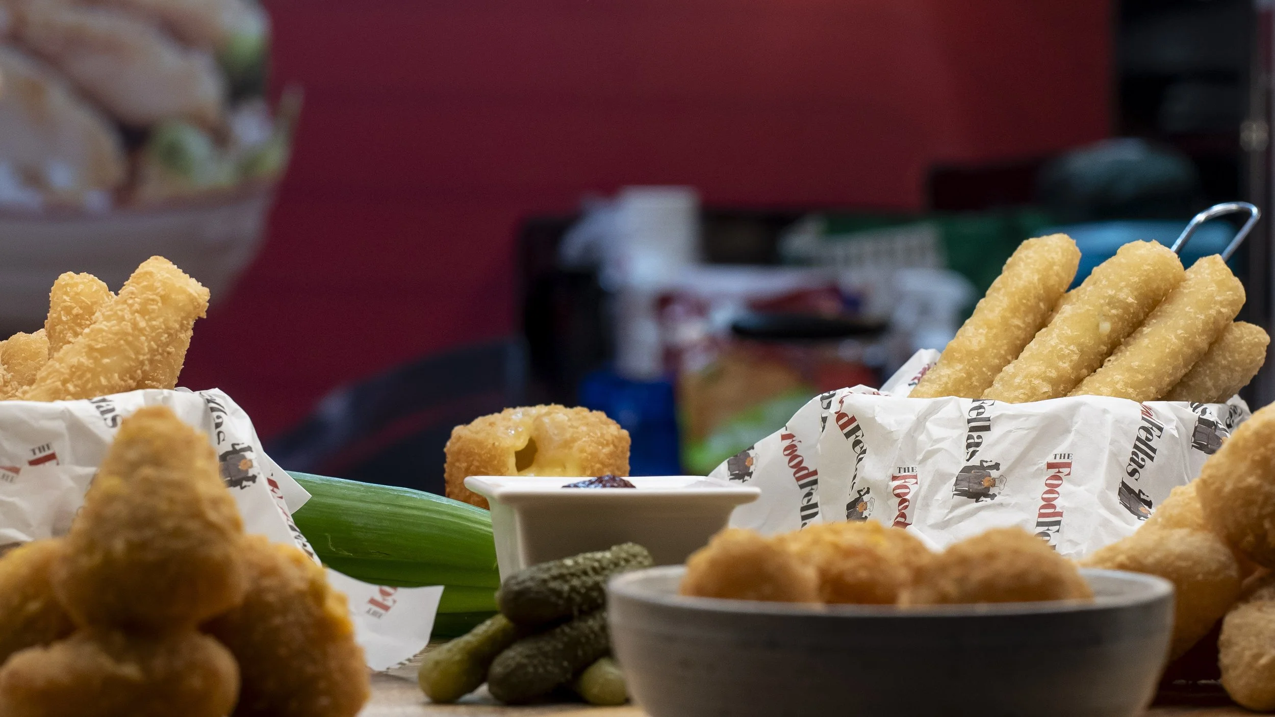 Baskets of golden fried bites served with gherkins and a dip on a food stand