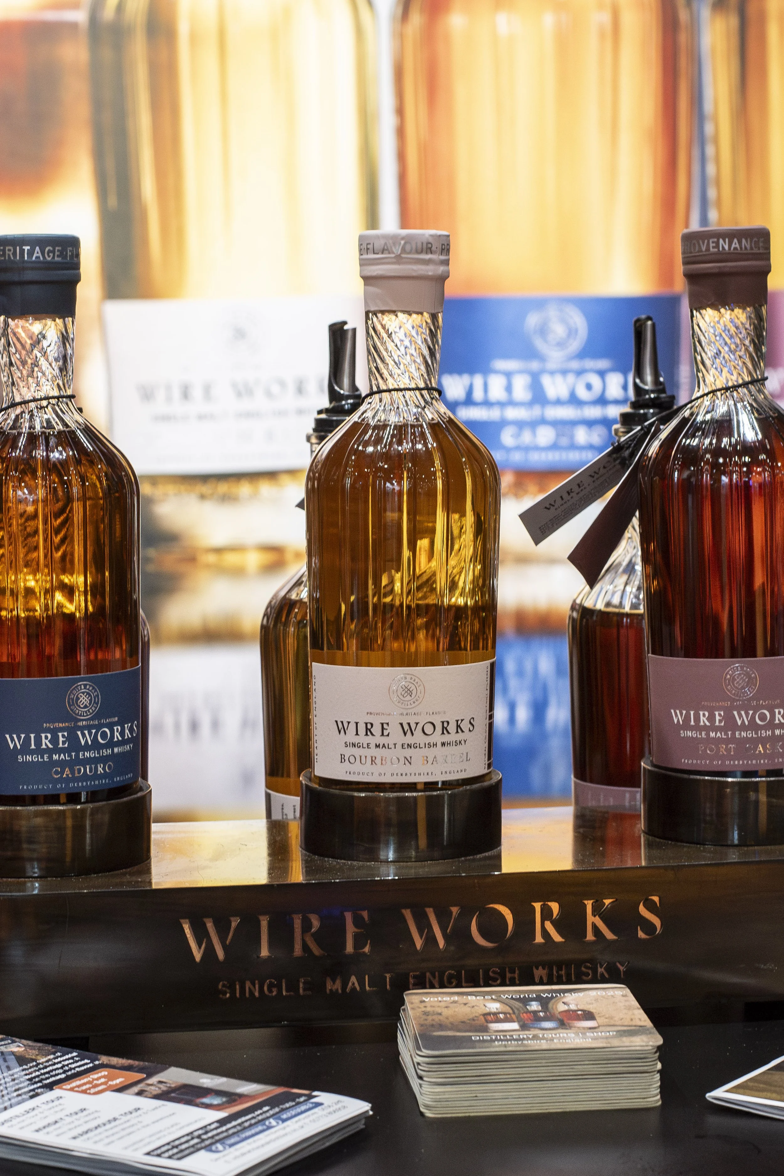 Wire Works whisky bottles displayed on a branded stand
