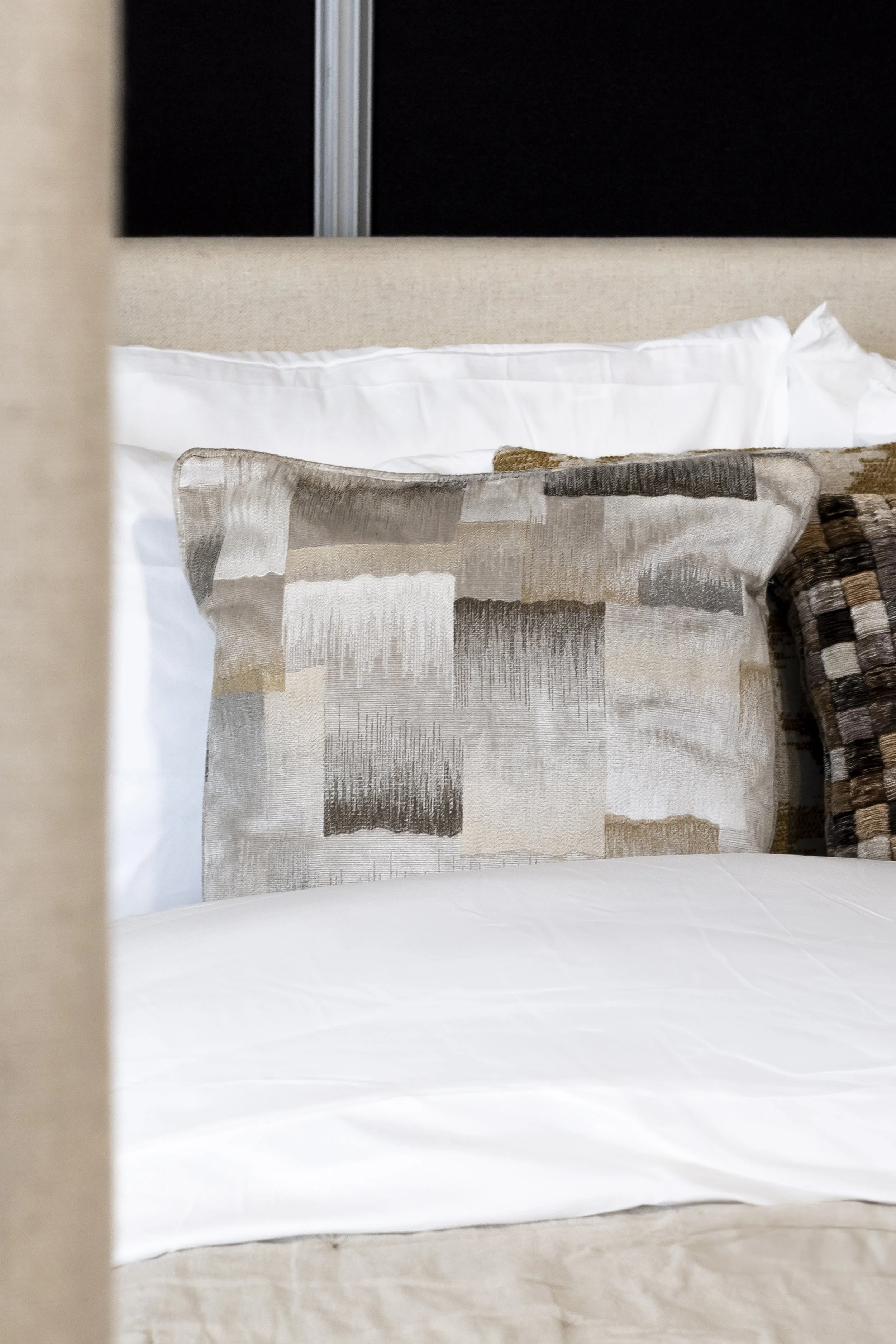 Close-up of a patterned cushion on a hotel bed_Furnishing Futures