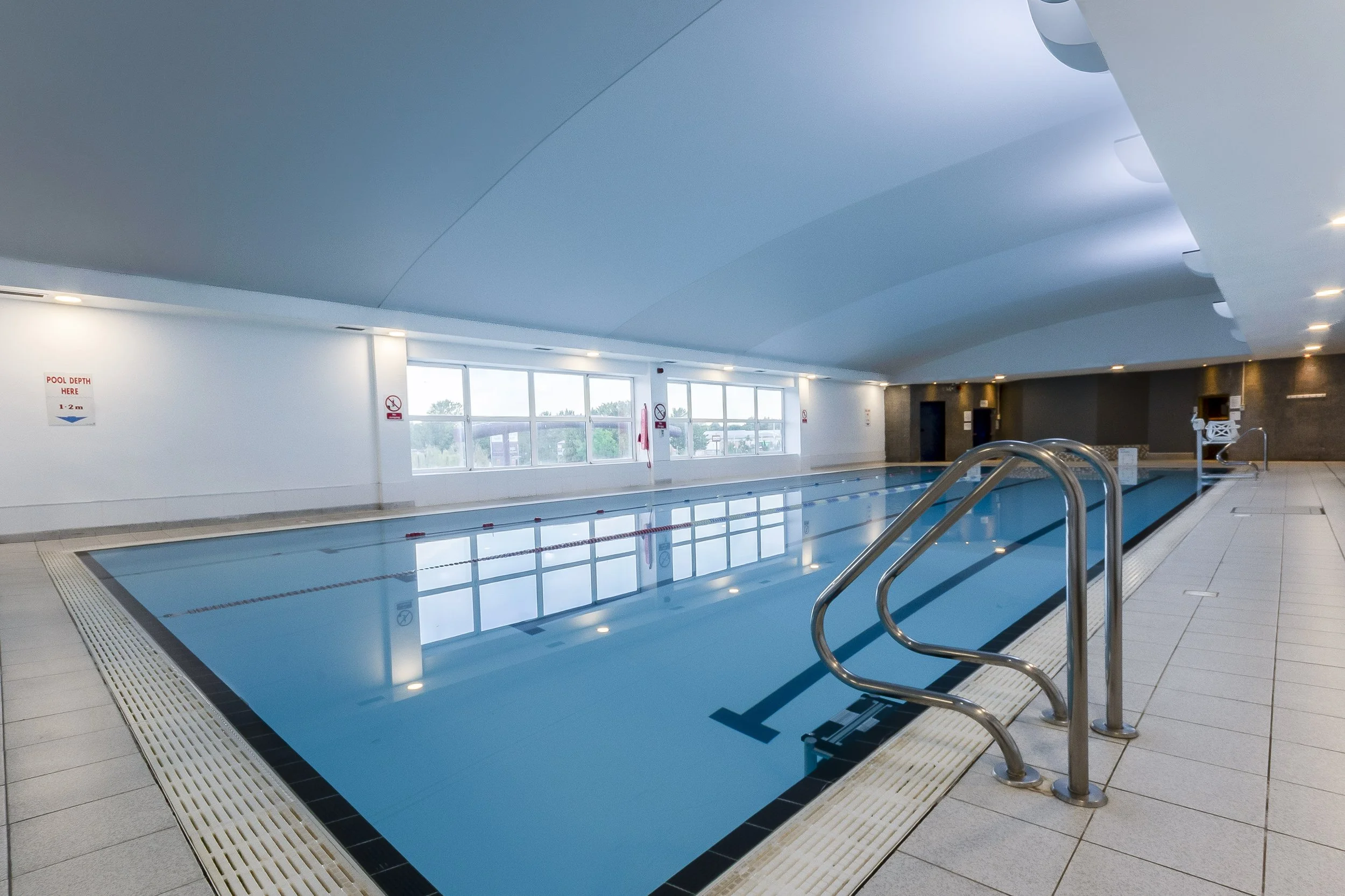 Swimming pool with handrail steps and a bright, high ceiling