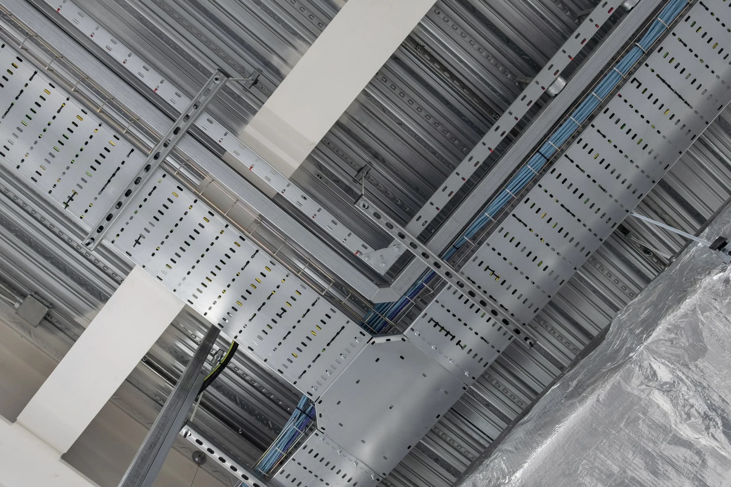 Overhead detail of cable trays and ductwork in the warehouse ceiling