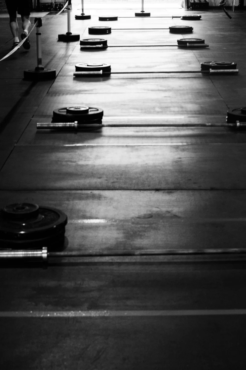 A black and white photo of a gym floor with barbells on it