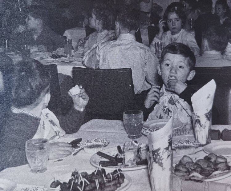black and white photo of children eating cake at a party, one boy is really going for it.jpg