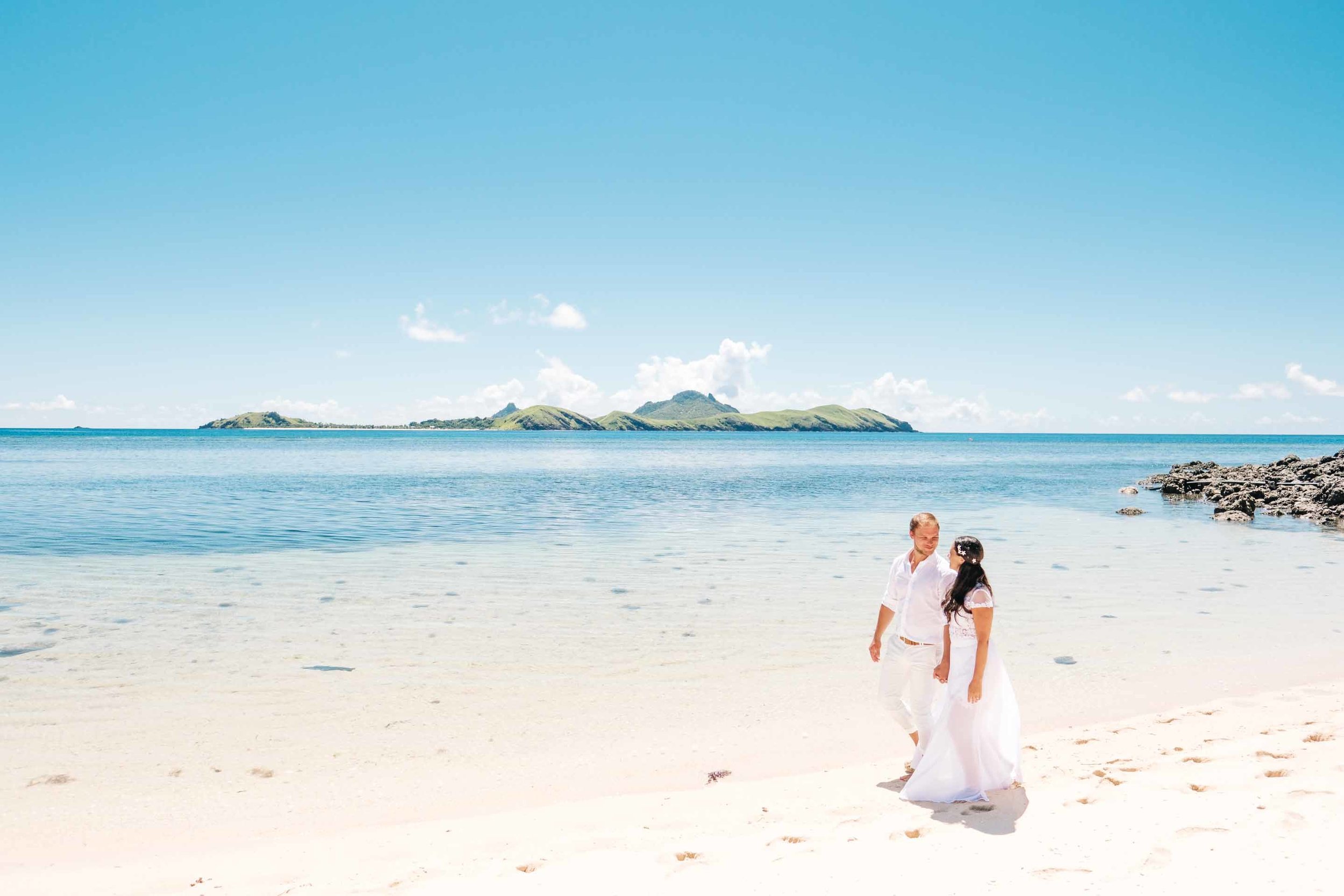 the couple walk along the white sandy beach of Sheraton Resort & Spa, Tokoriki Island