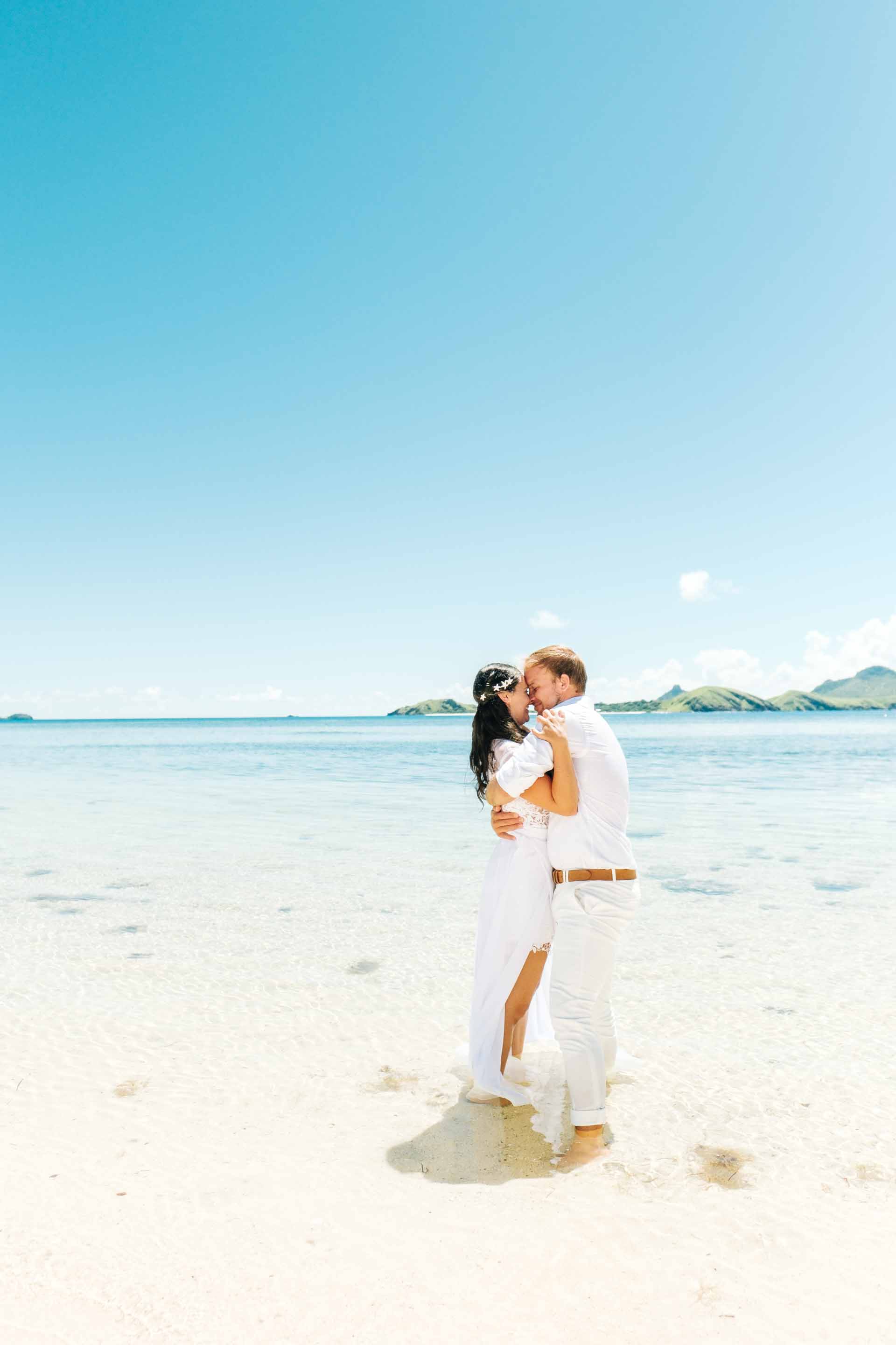 the couple hold each other close at they stand in the shallow waters of the South Pacific