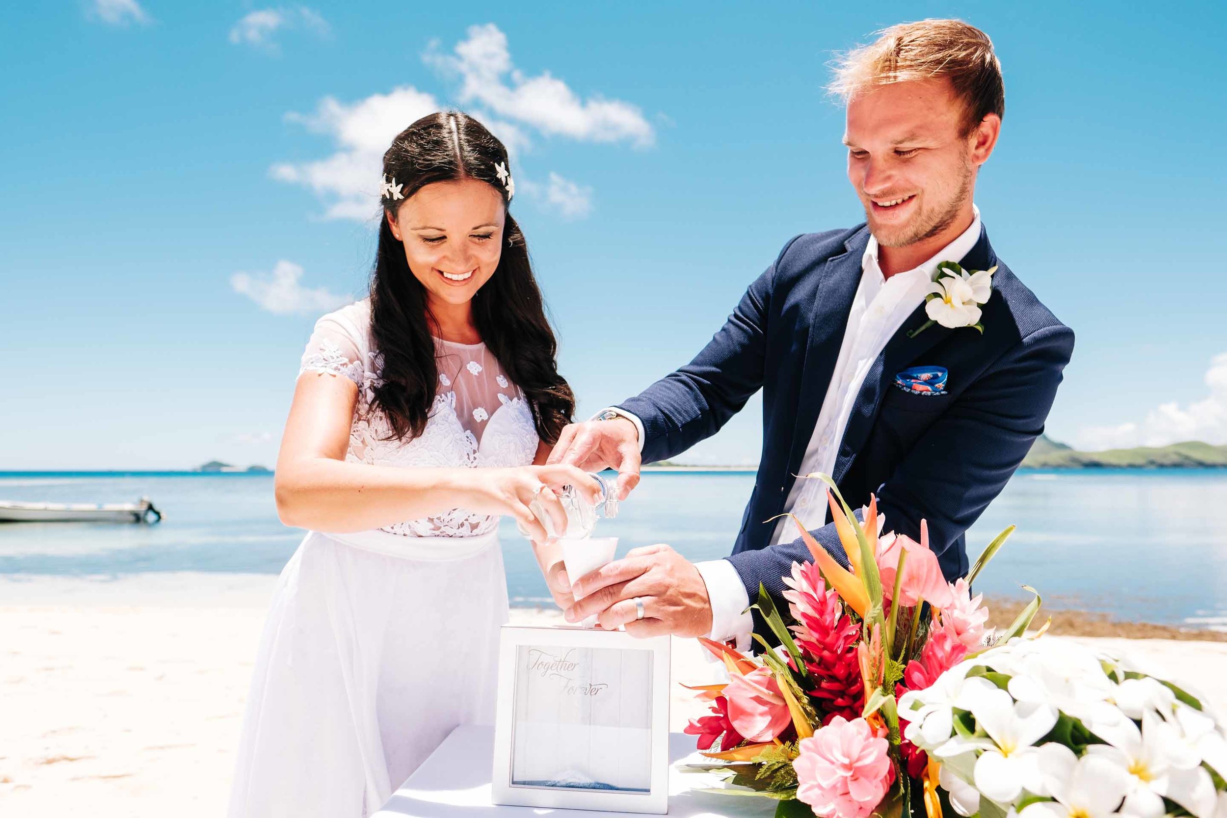 the couple pour sand of different colours into a container as part of a sand ceremony