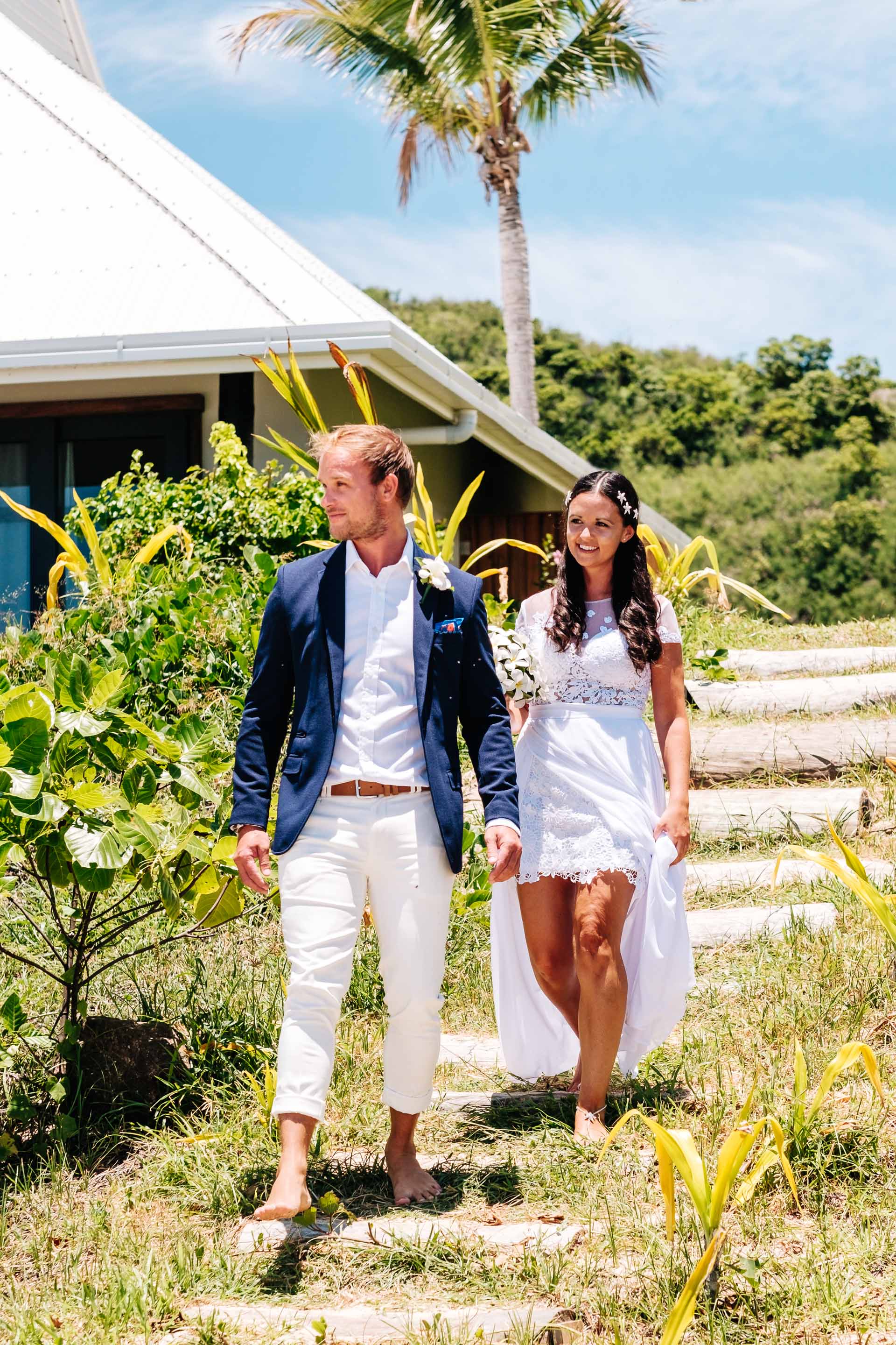 the groom leading the bride down the steep pathway to the beach and their wedding ceremony