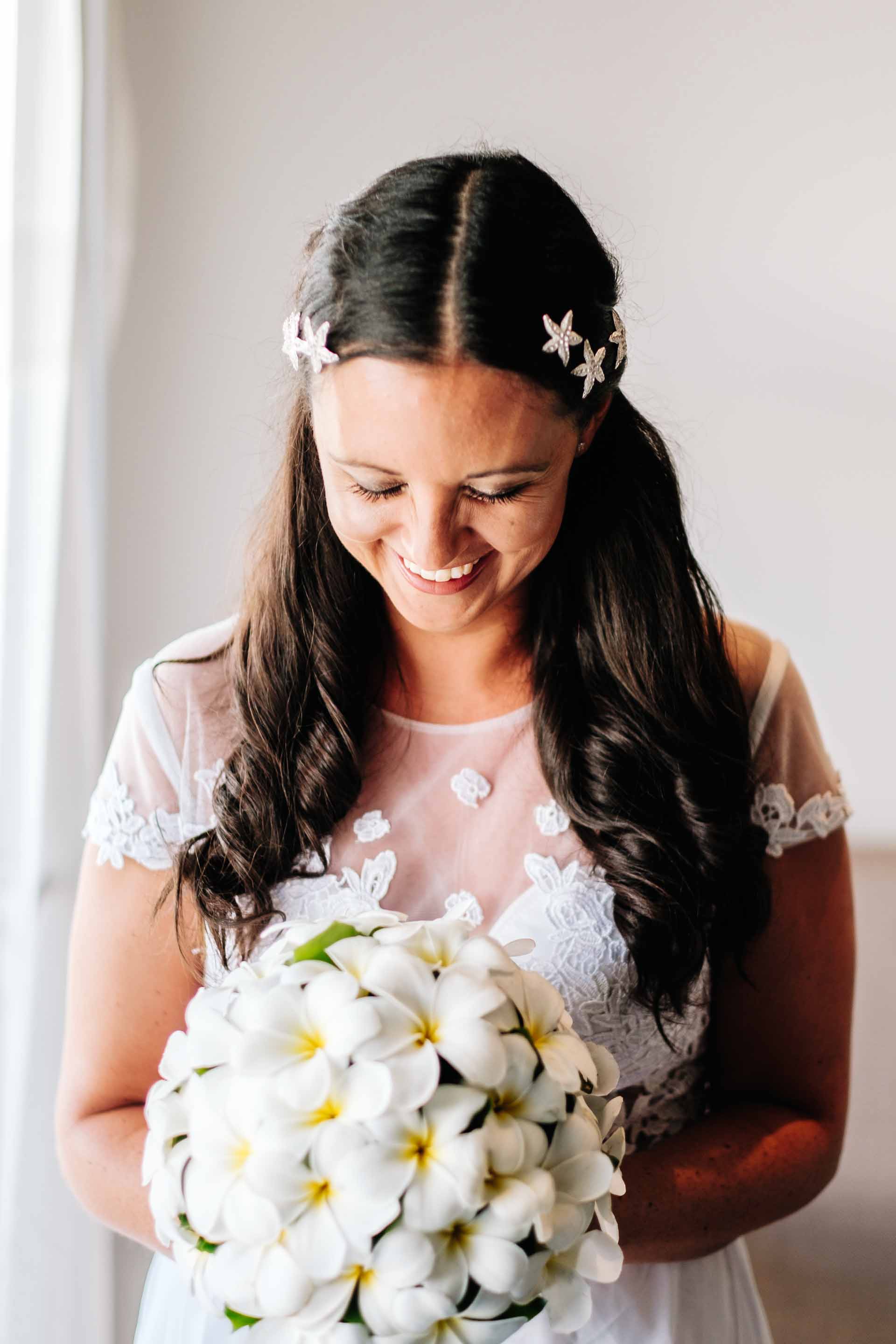 a colour portrait of the bride laughing while holding her flowers by the window