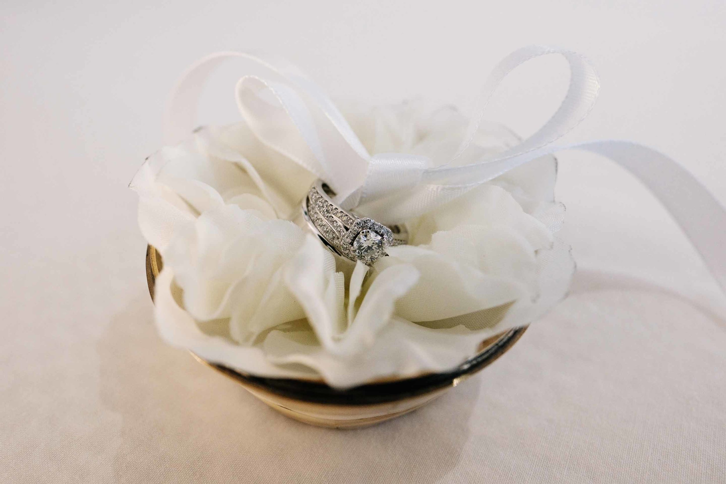 Wedding rings tied together with ribbon in a customised ring holder