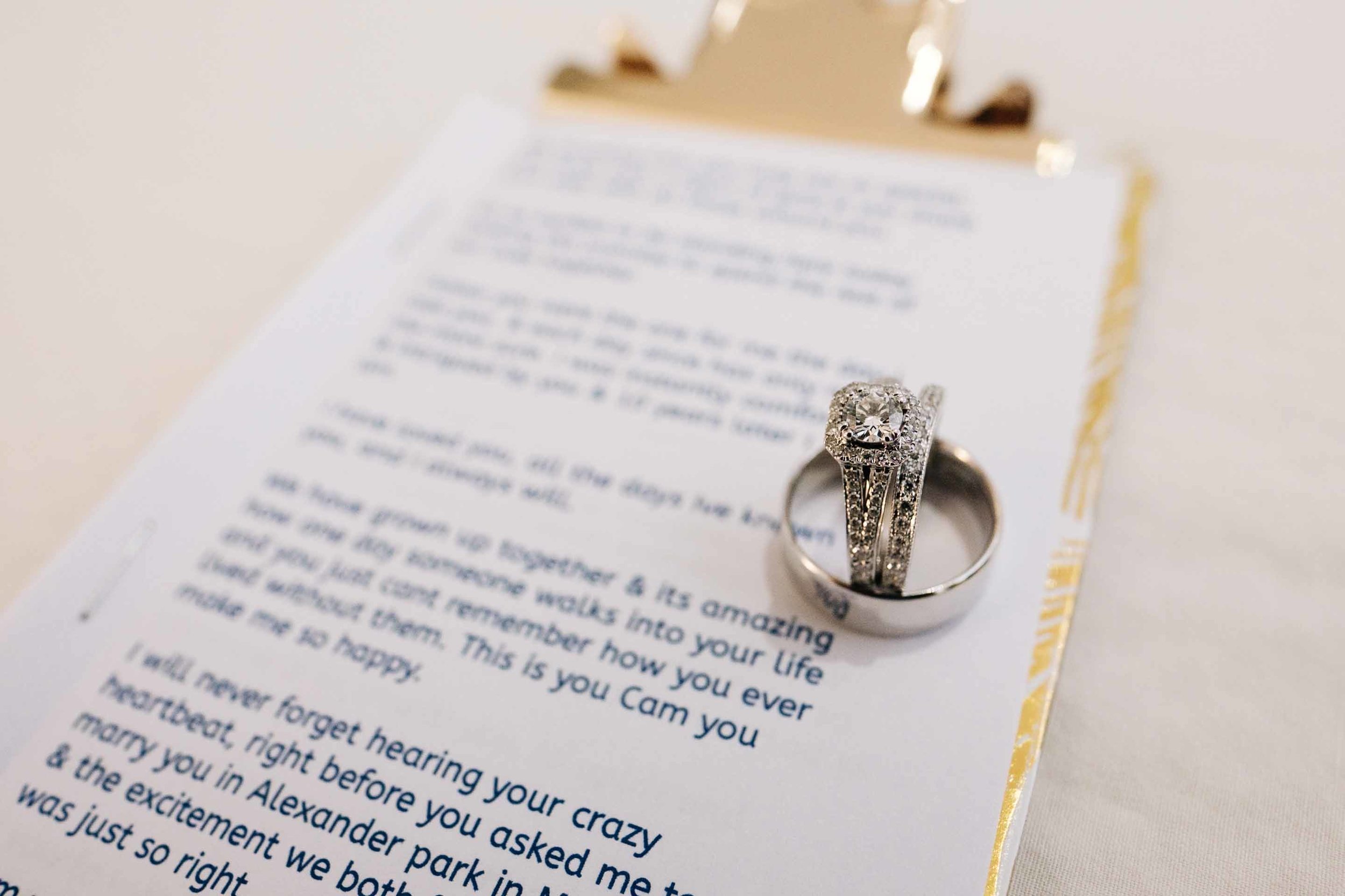 wedding rings placed on the bride Holly's vows neatly printed and placed in a custom gold clipboard