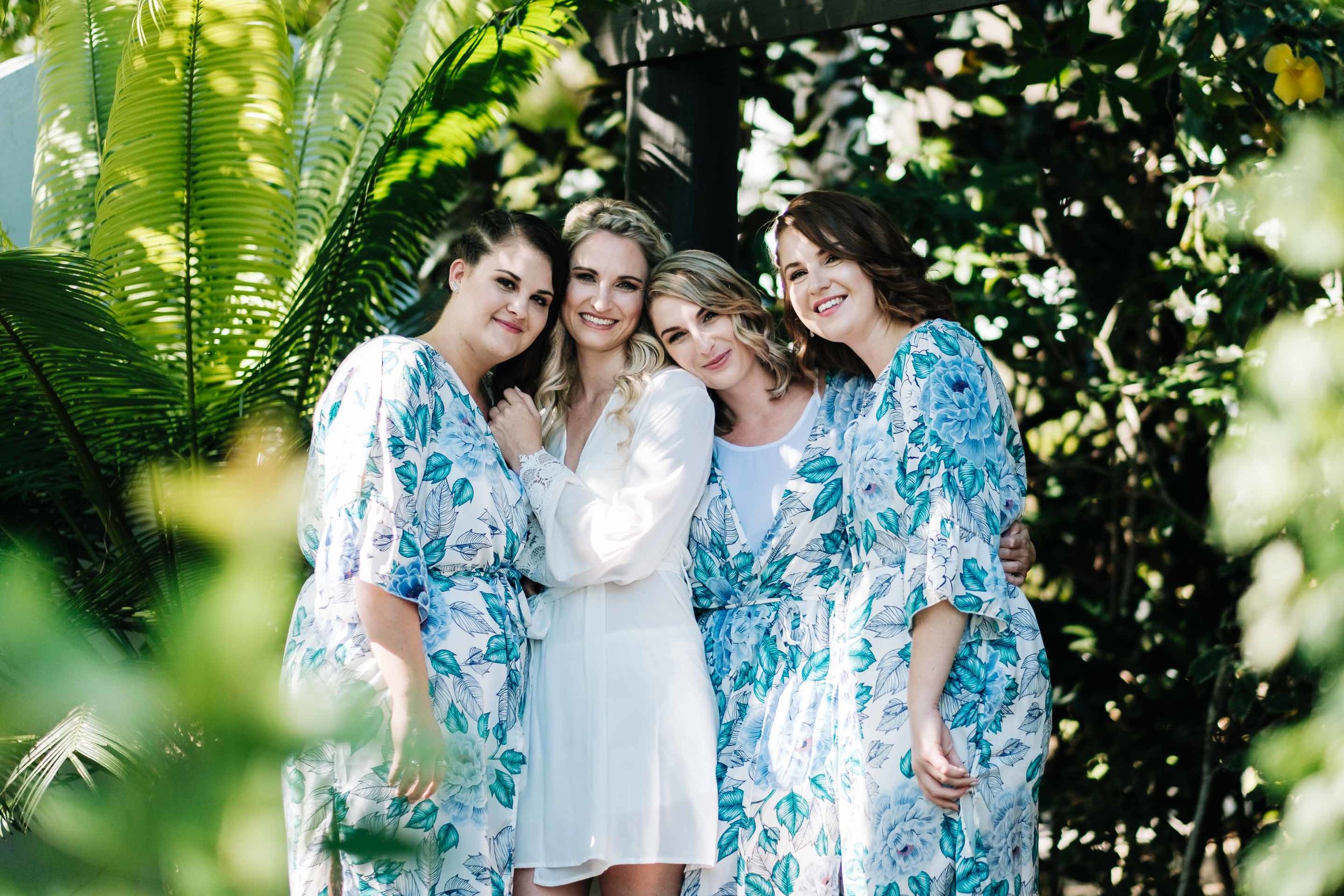 the bride Holly and her bridesmaids in their tropical floral robes outside their room under the pergola