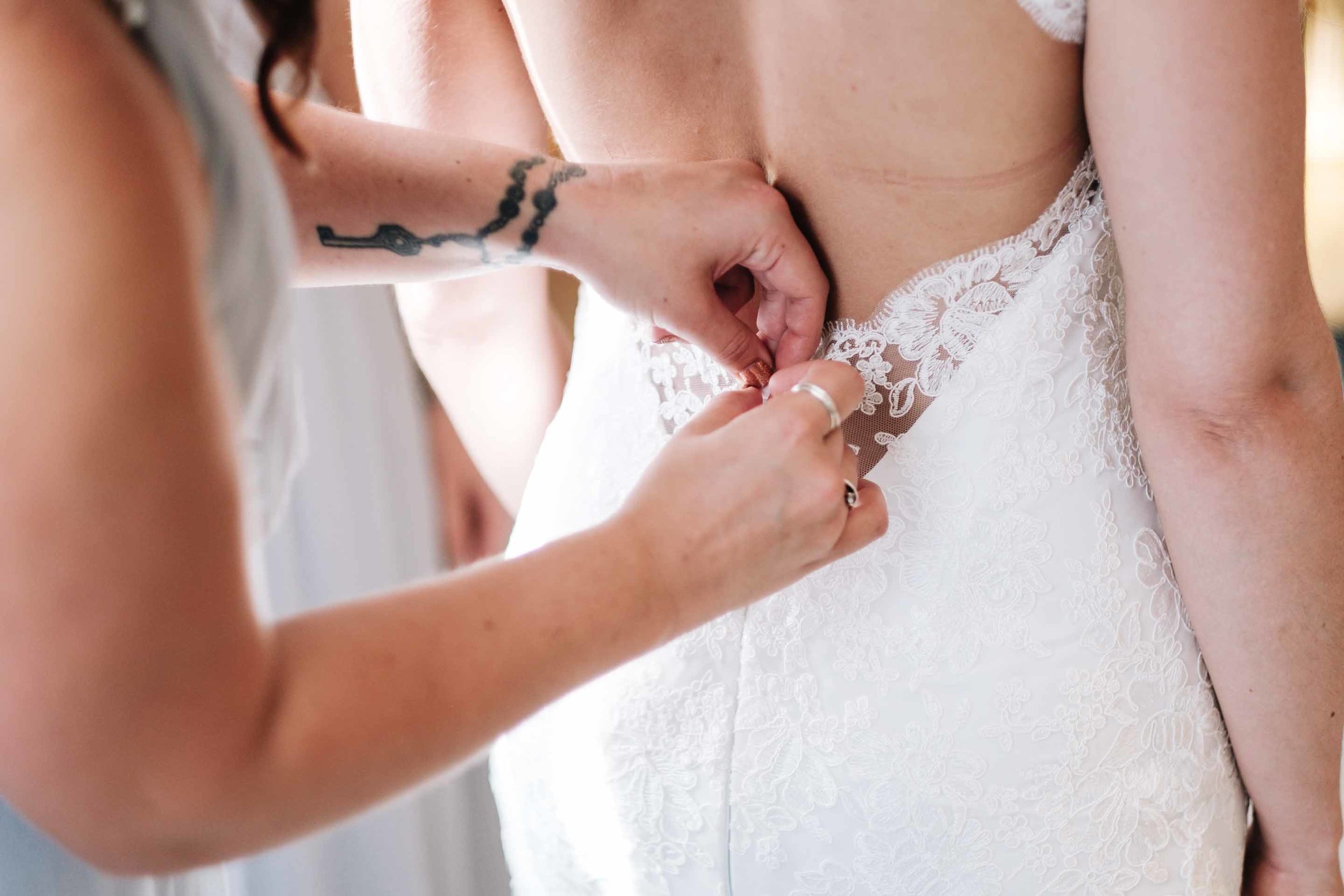 a bridesmaid zipping up the wedding dress