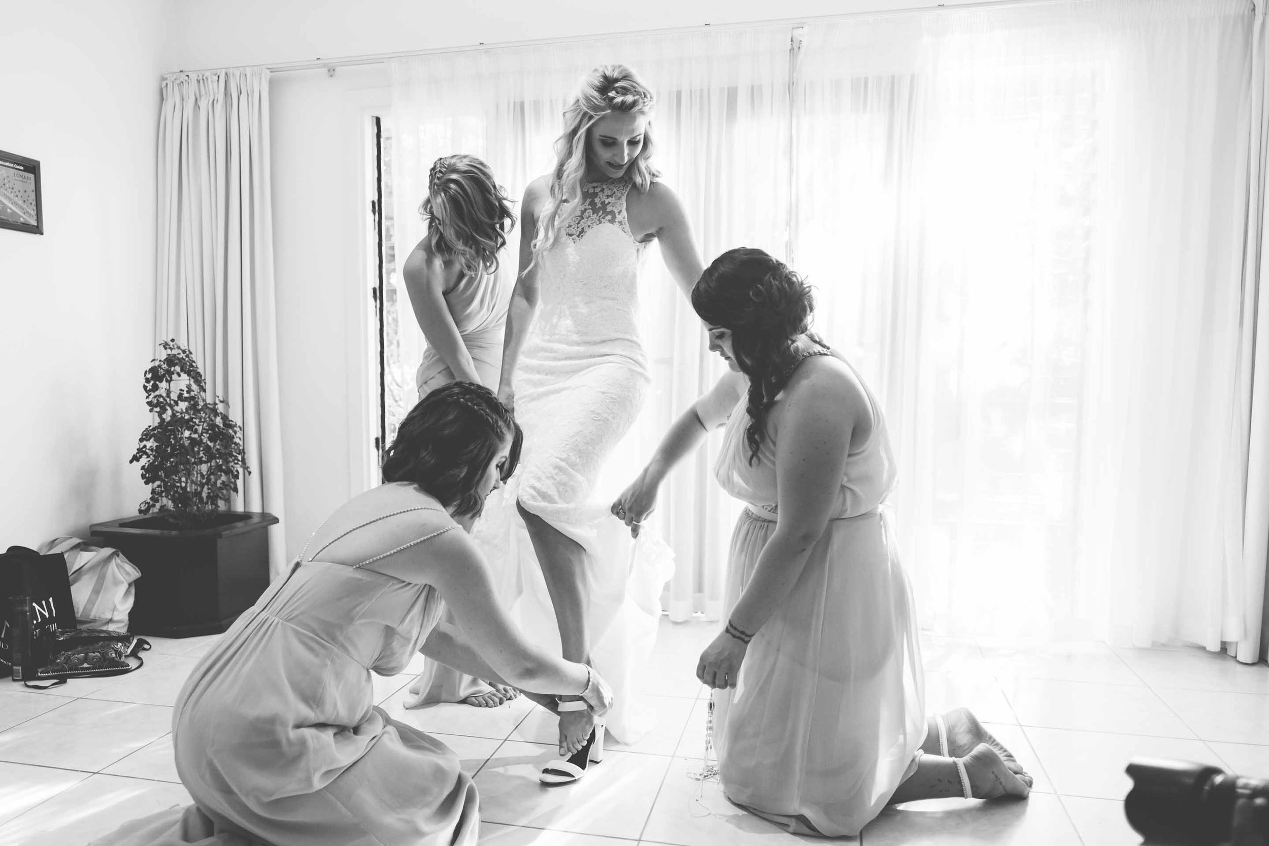 the bridesmaids helping the bride into her heels