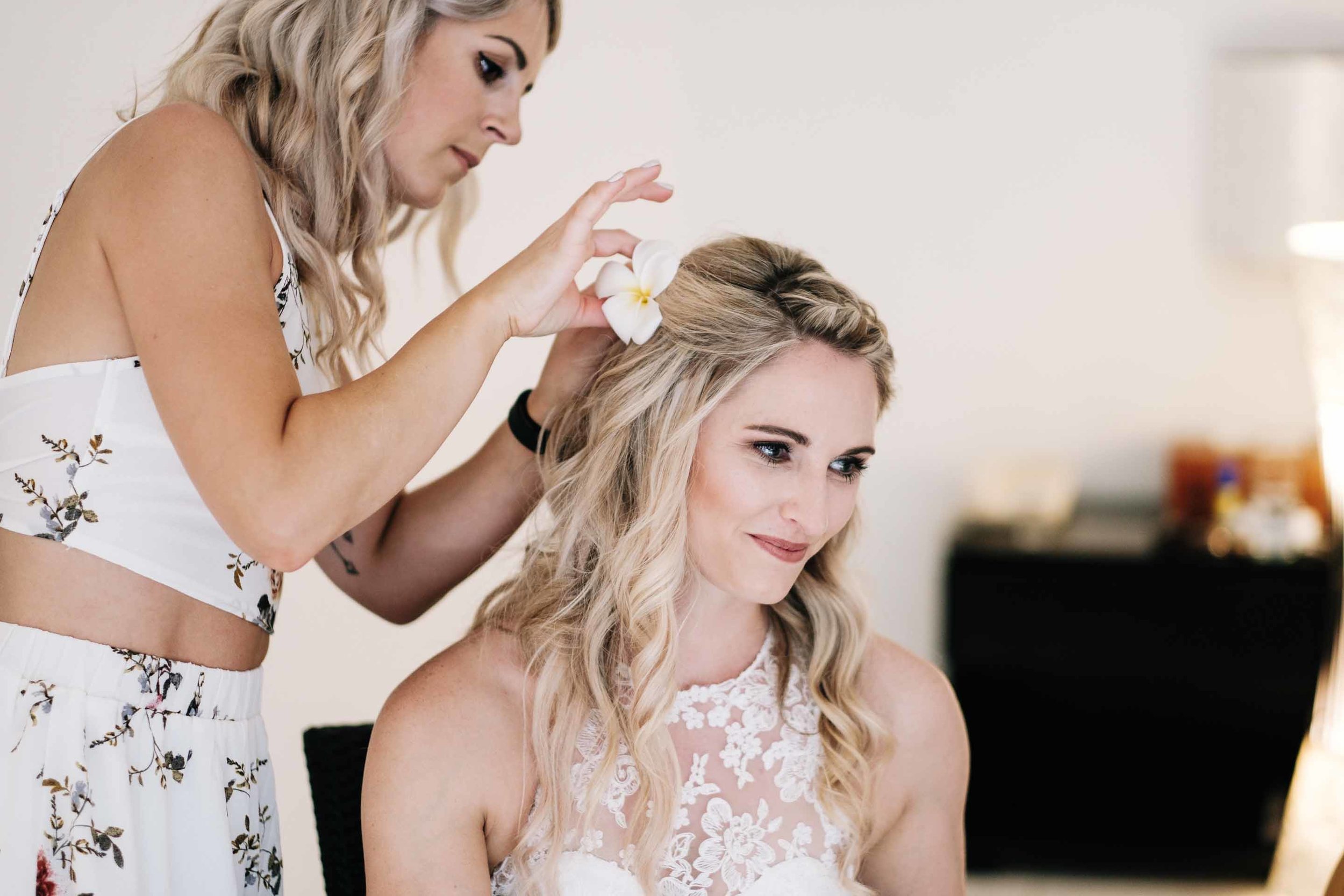 the makeup artist placing a flower into the brides hair