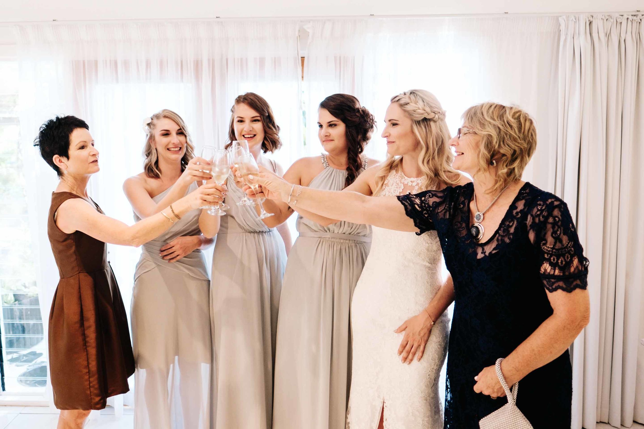 the bride and bridesmaids with the brides mother and aunt having a celebratory glass of champagne before the ceremony