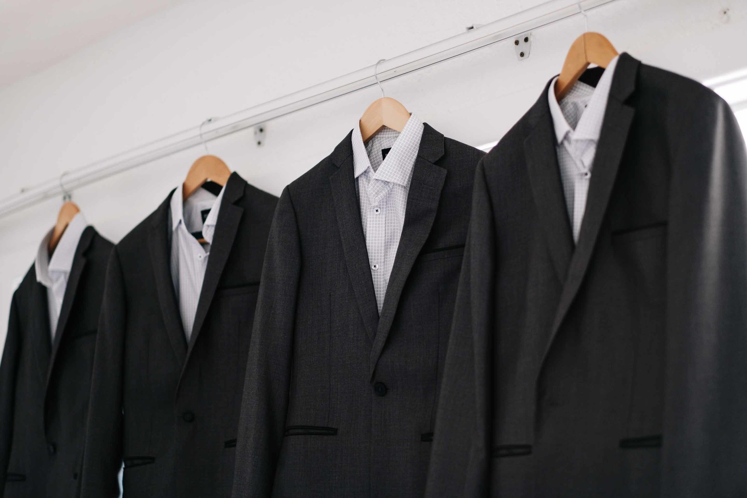 the groom and groomsmen suits hanging from customised wooden hangers