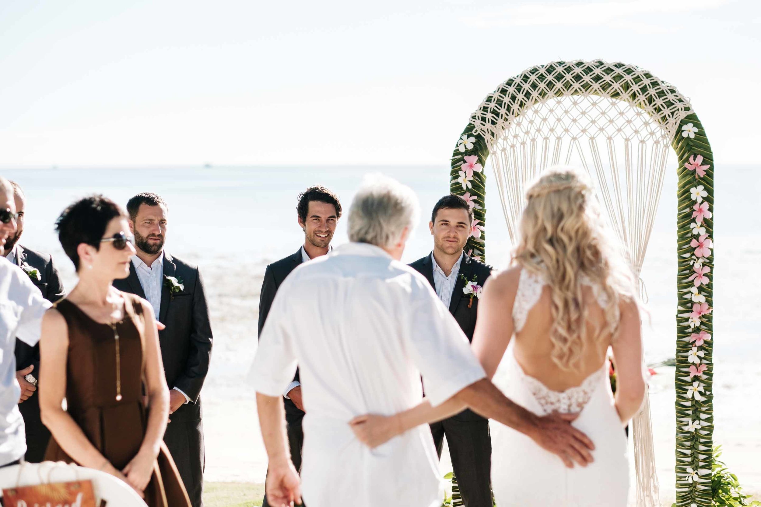 the groom smiling as he watches his bride walk down the aisle