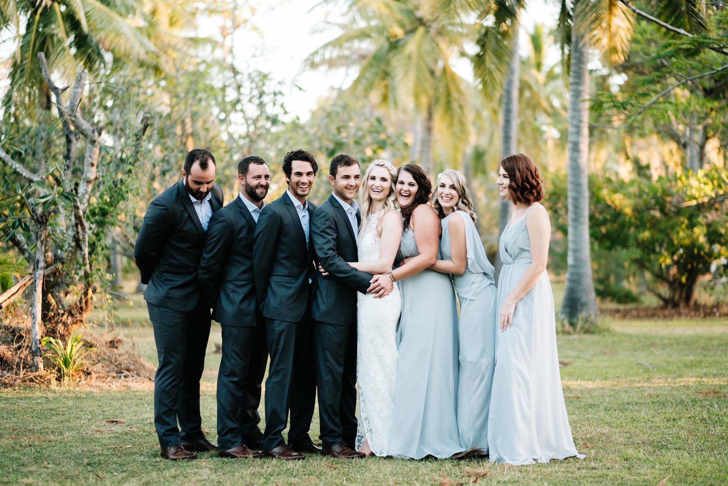 the bridal party together in the grounds behind Lomani Island Resort sharing a group hug