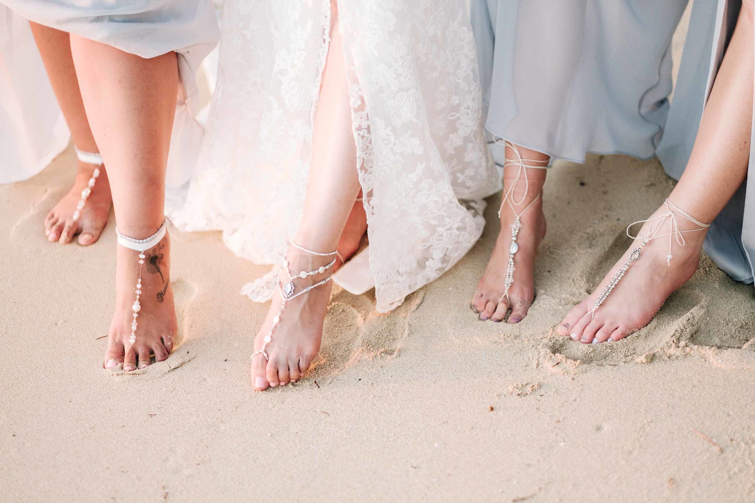 the bridesmaids showing off their foot jewellery on the white sand beach in front of the Resort