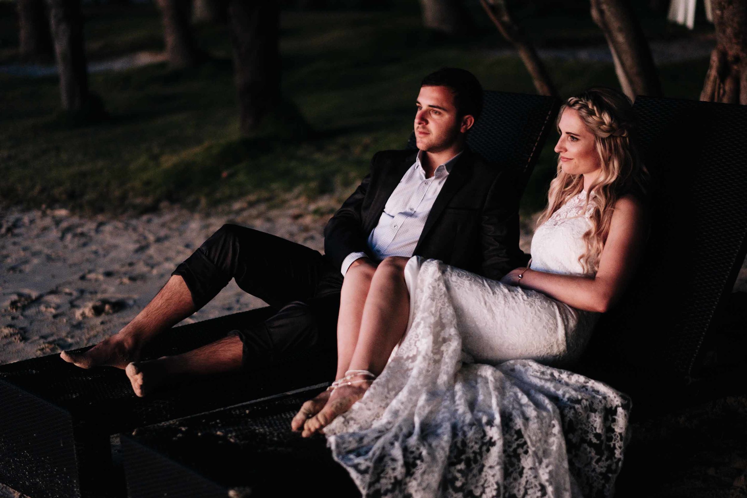 the bride and groom side by side on sun loungers as they wait for photos at sunset