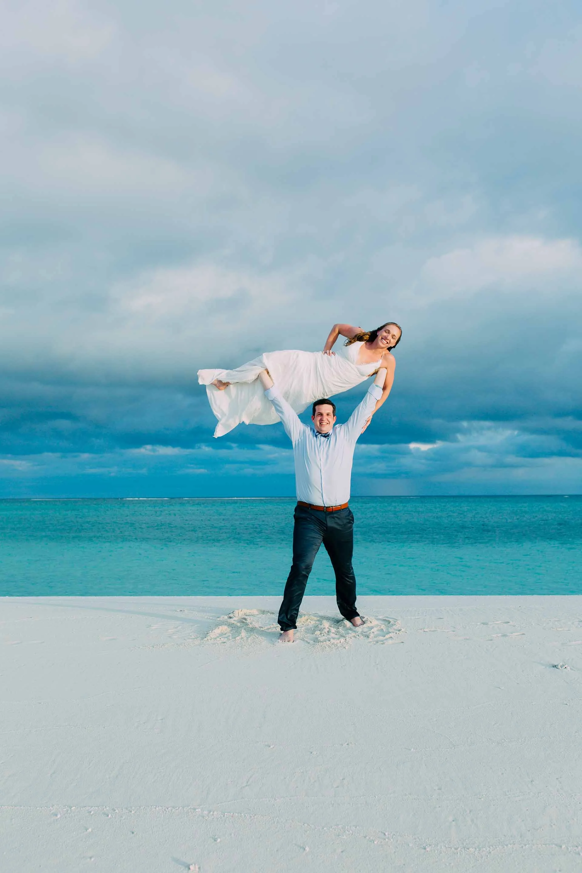 Gym junkies just married and no threshold heres the solution. Groom holds Bride over his head. Just married in paradise.