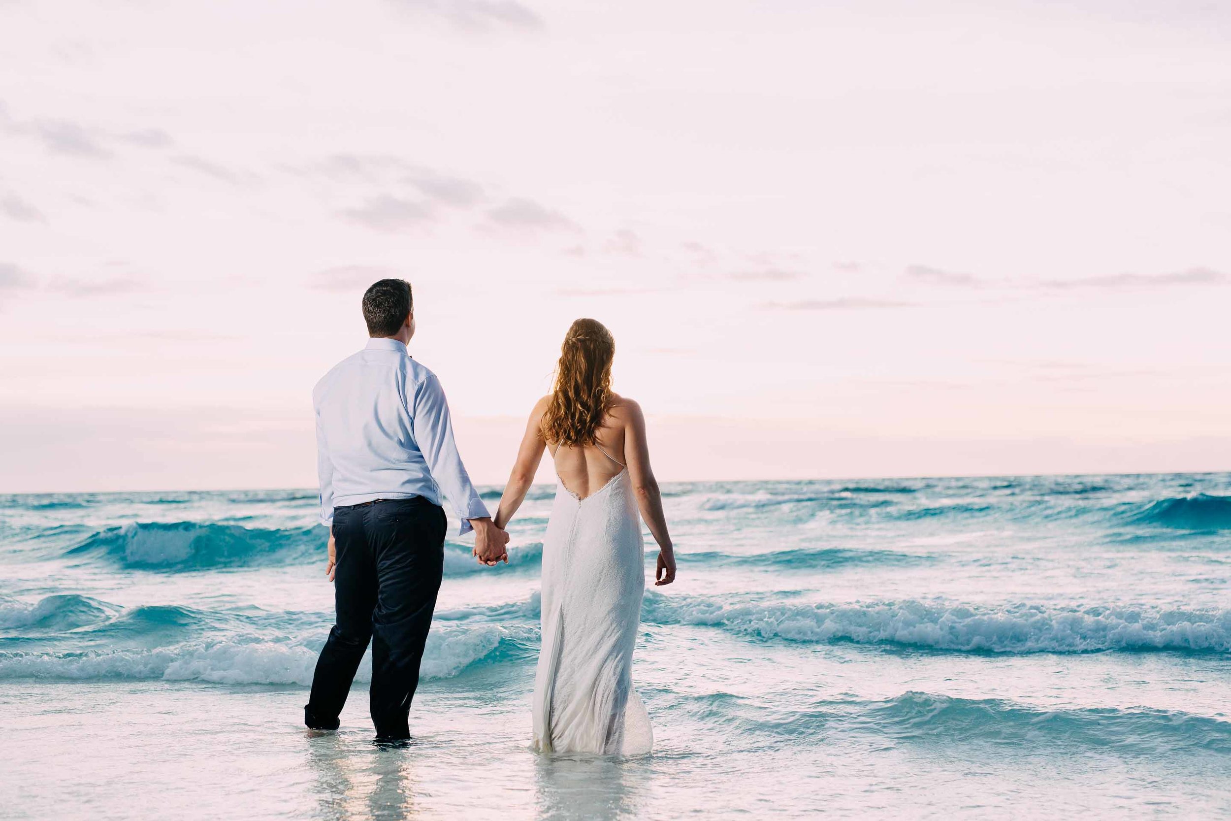 Newlyweds wade into the warm South Pacific Ocean moments after getting married on the sand quay. 