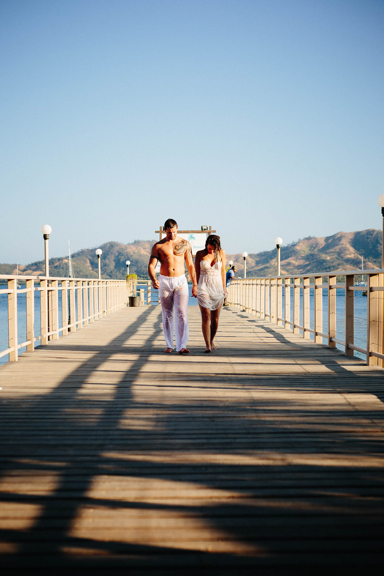 couple walking down the jetty after their trash-the-dress session