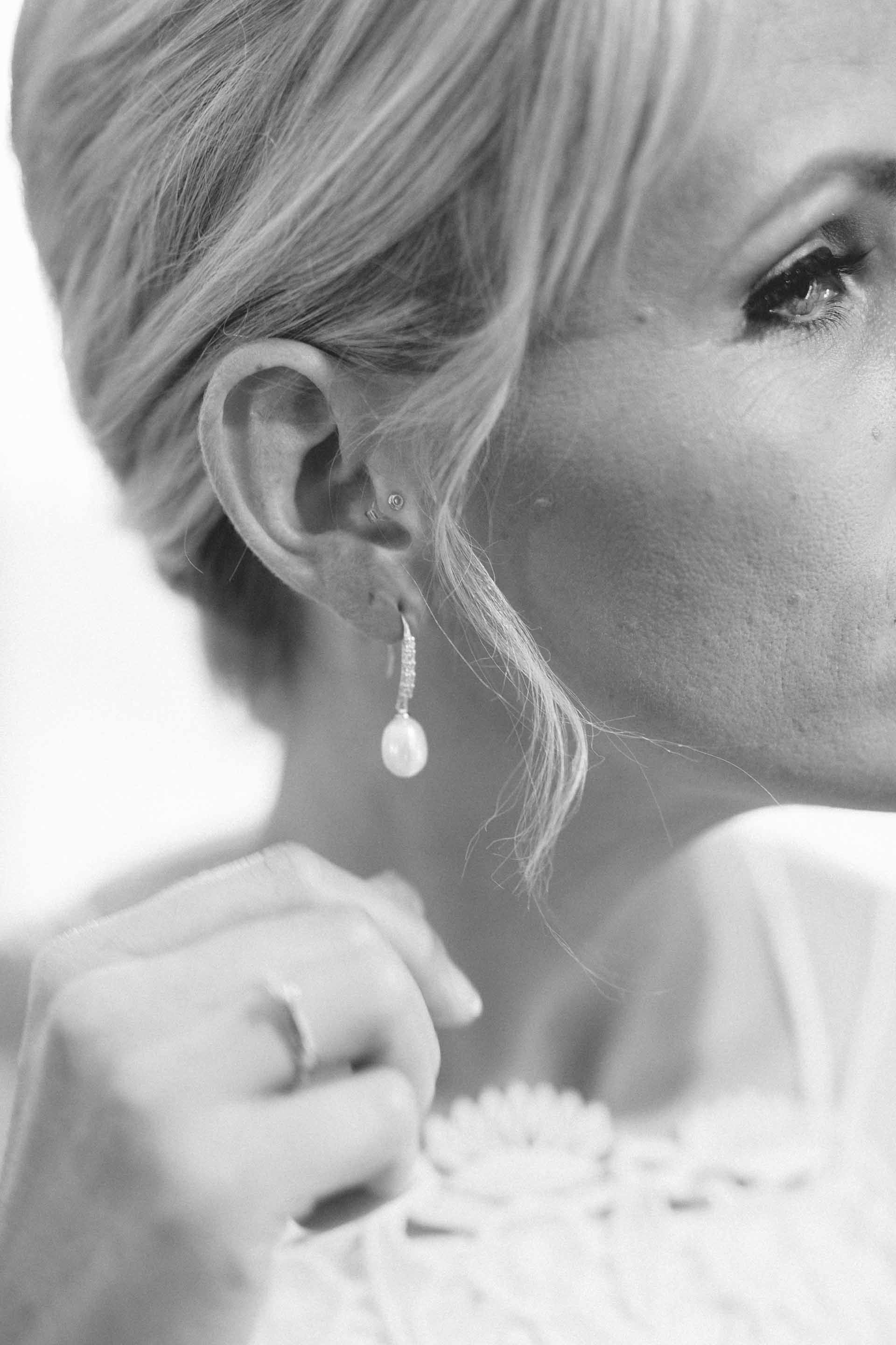 the bride putting on her pearl earrings